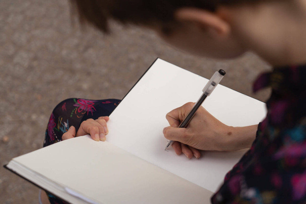 Personal Branding Photography. Why Is It Important Fedor Vasilev Photographer In Berlin Close-up of a person writing in a blank sketchbook with a black pen while sitting outdoors