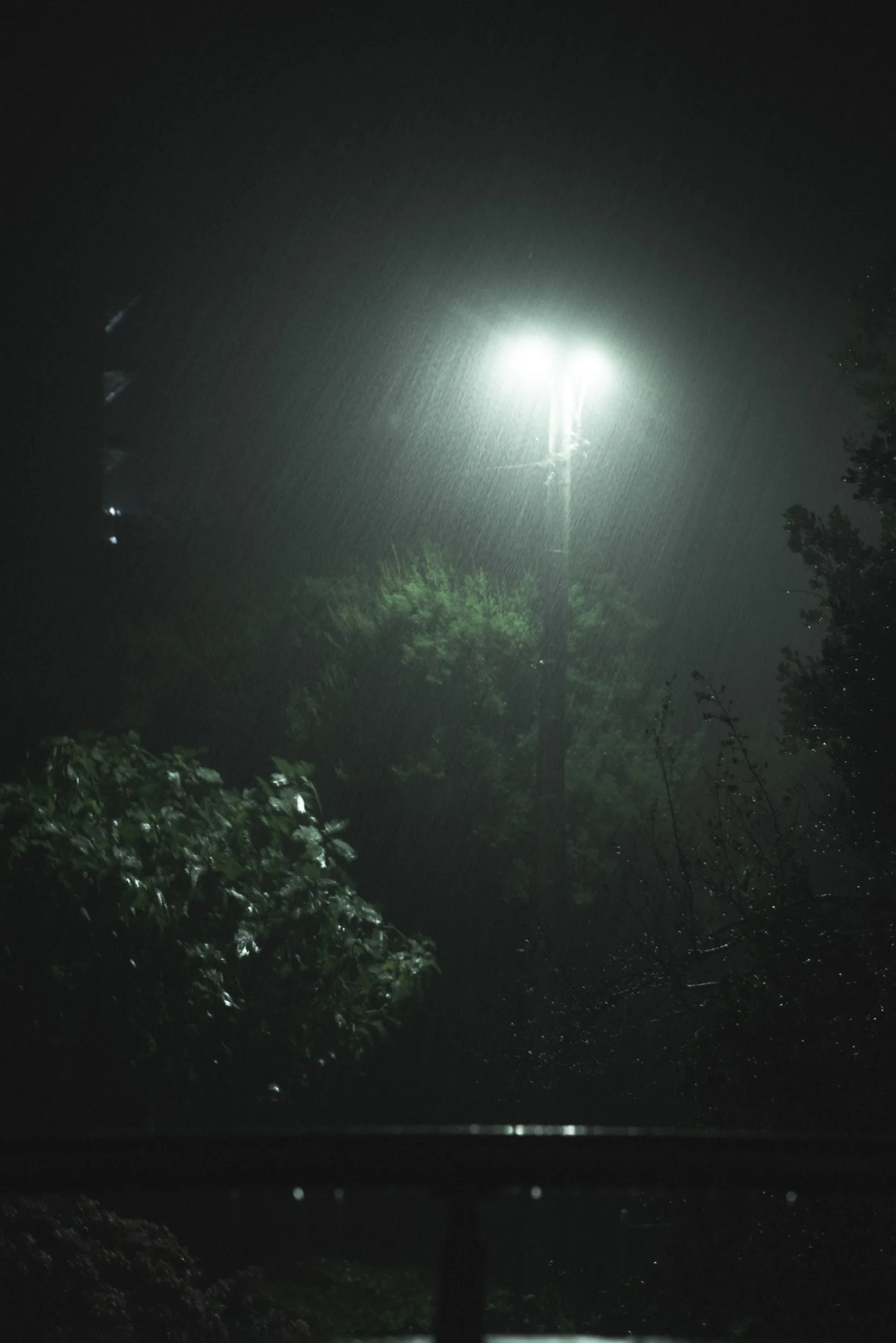Heavy rainy photograph at night with a white streetlamp