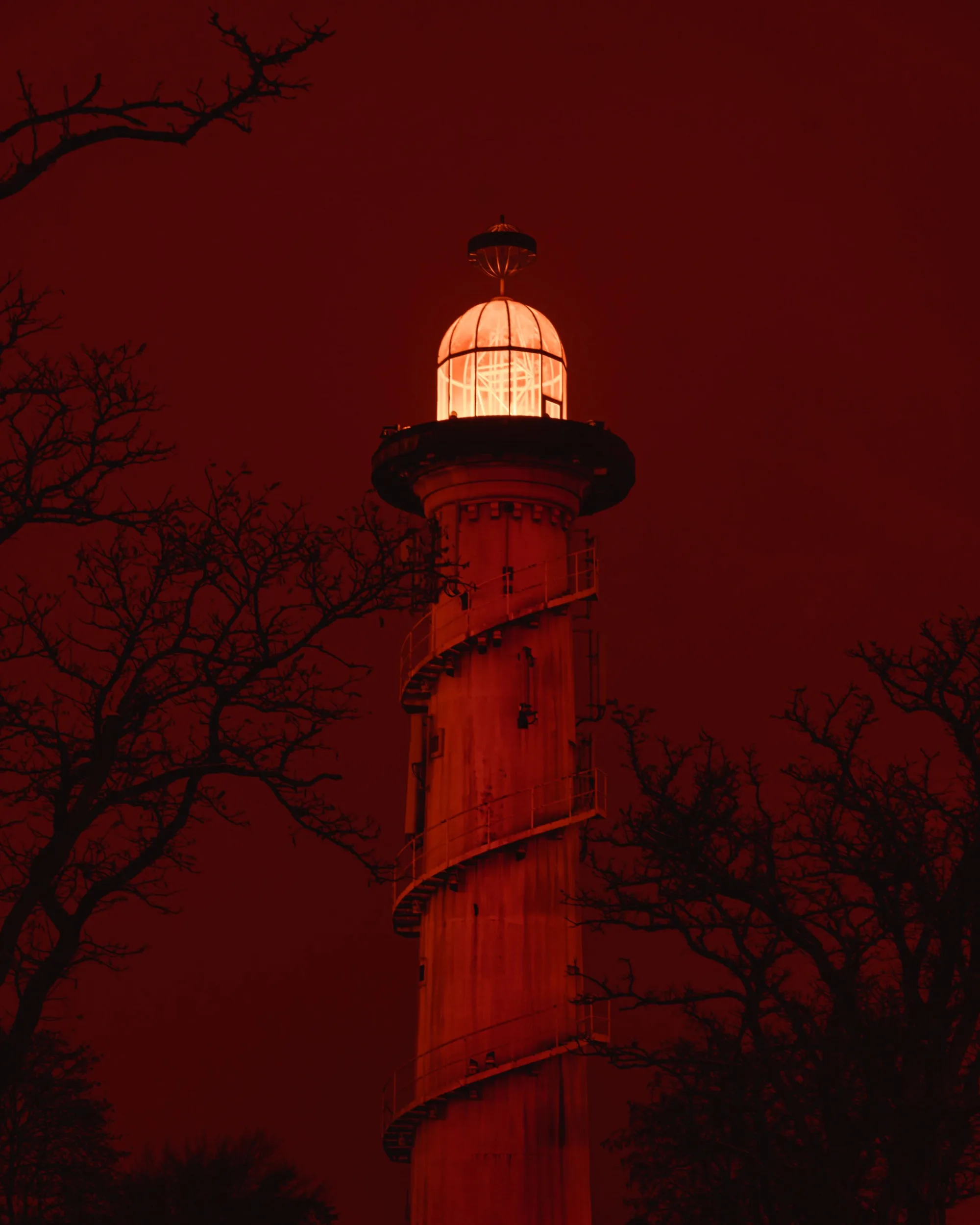 Red photograph with a lighthouse surrounded by trees