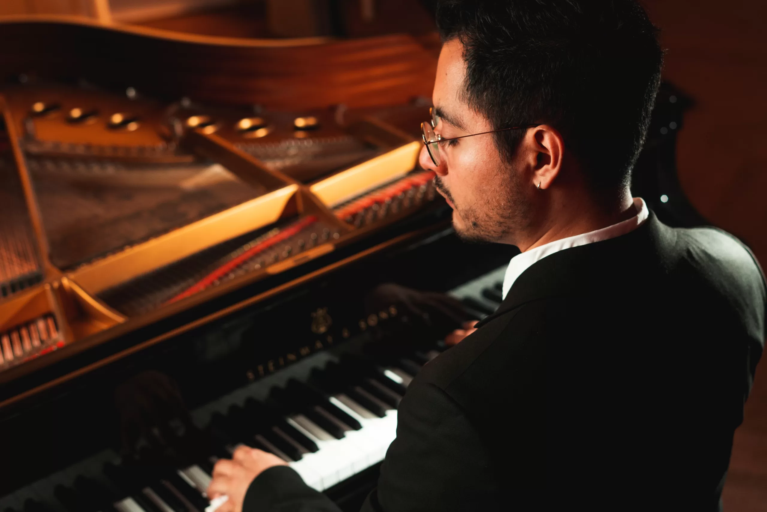 A pianist with a grand piano in a classical suit, at a dramatic angle by photographer in Berlin Fedor Vasilev