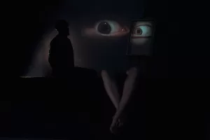 Fine art photograph with a man sitting in a dark room in front of eyes looking at him by photographer Fedor Vasilev