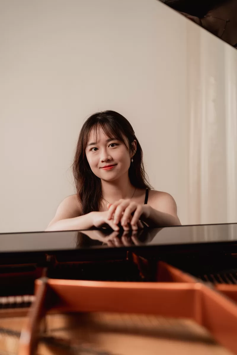 A portrait of a pianist leaning on a piano