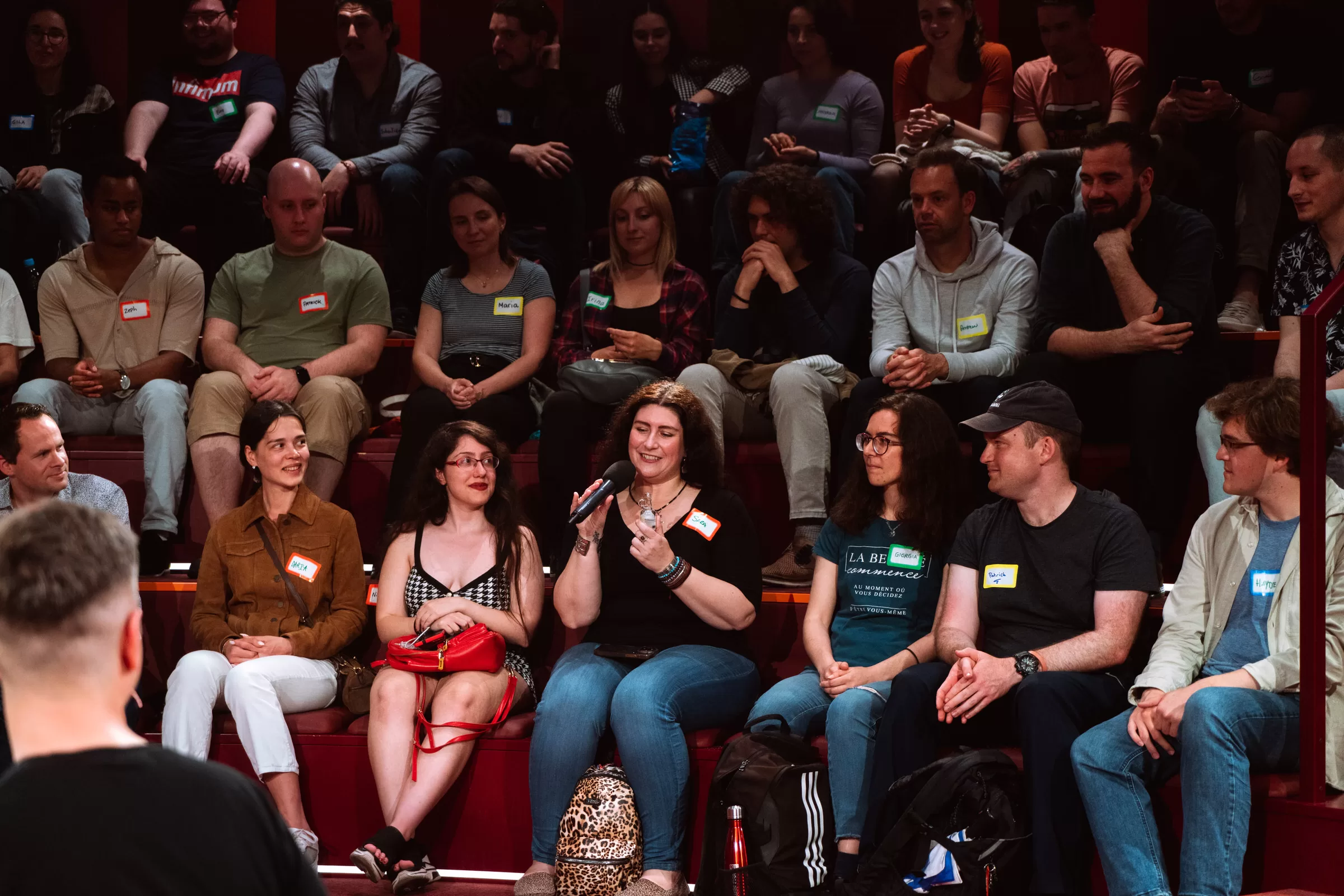 People on an event in a concert hall asking questions from event organisers
