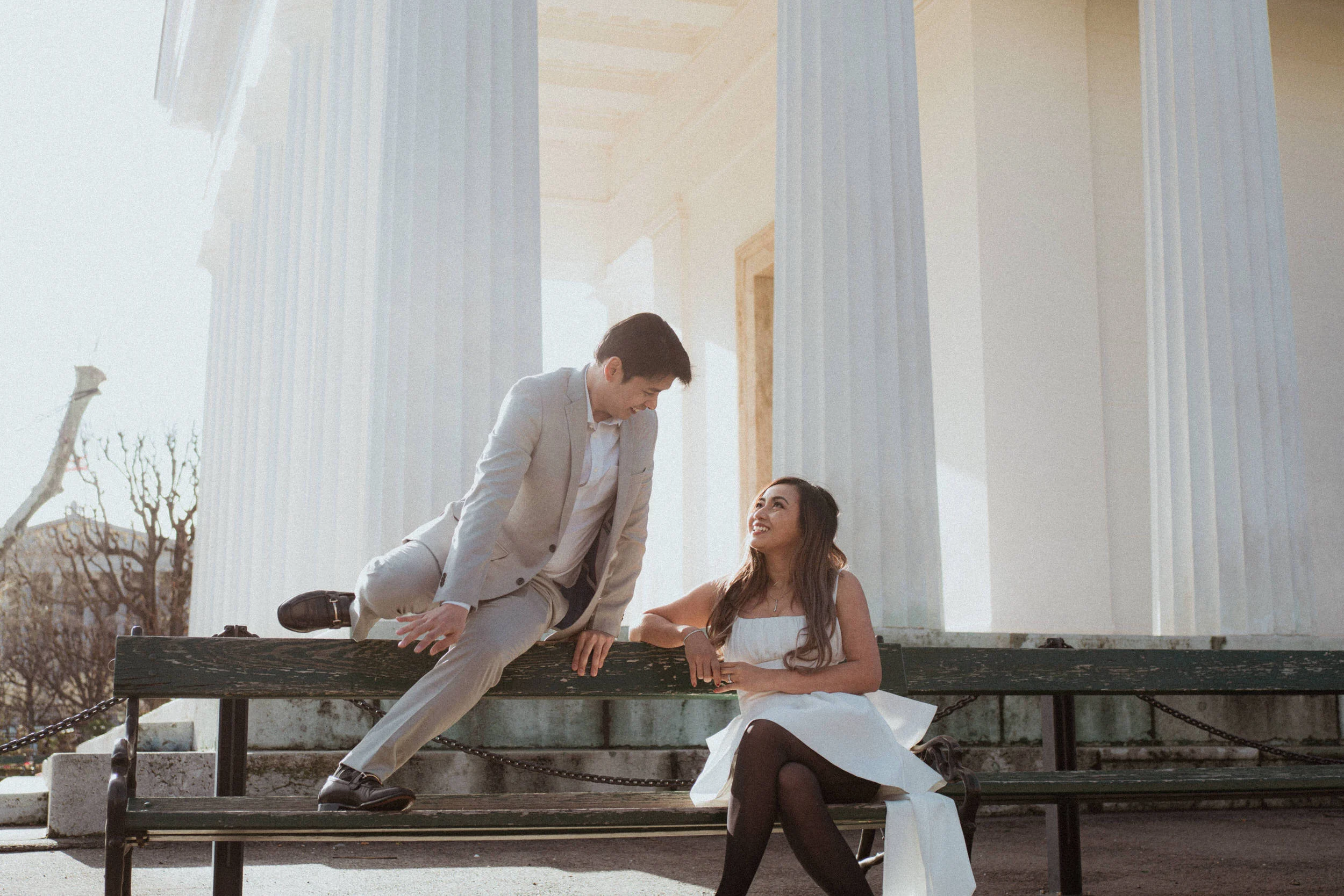 Lifestyle photo if a groom approaching his bride, jumping over a bench in Volksgarten in Vienna