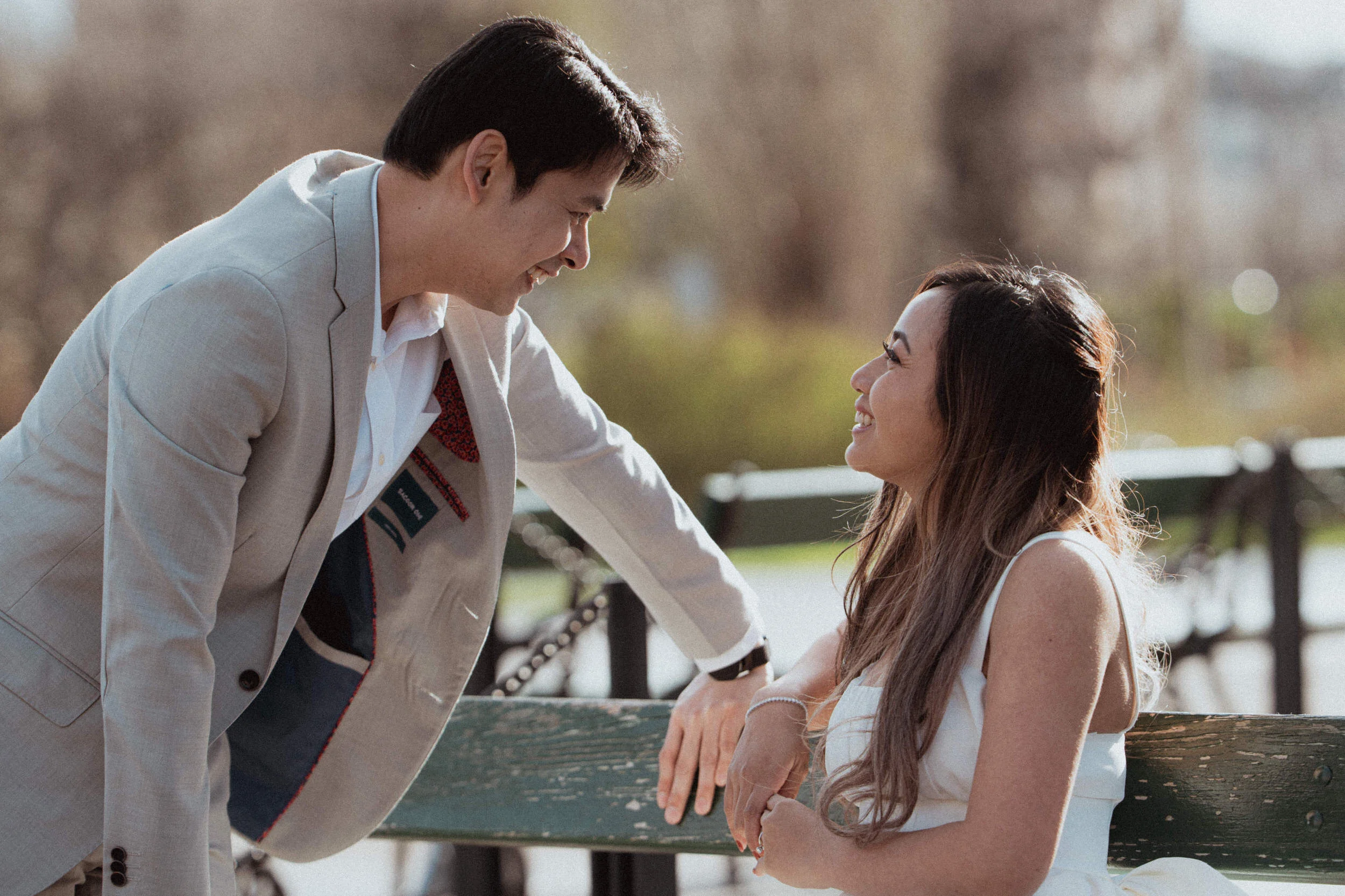 A man approaches his girlfriend on a bench at Volksgarten