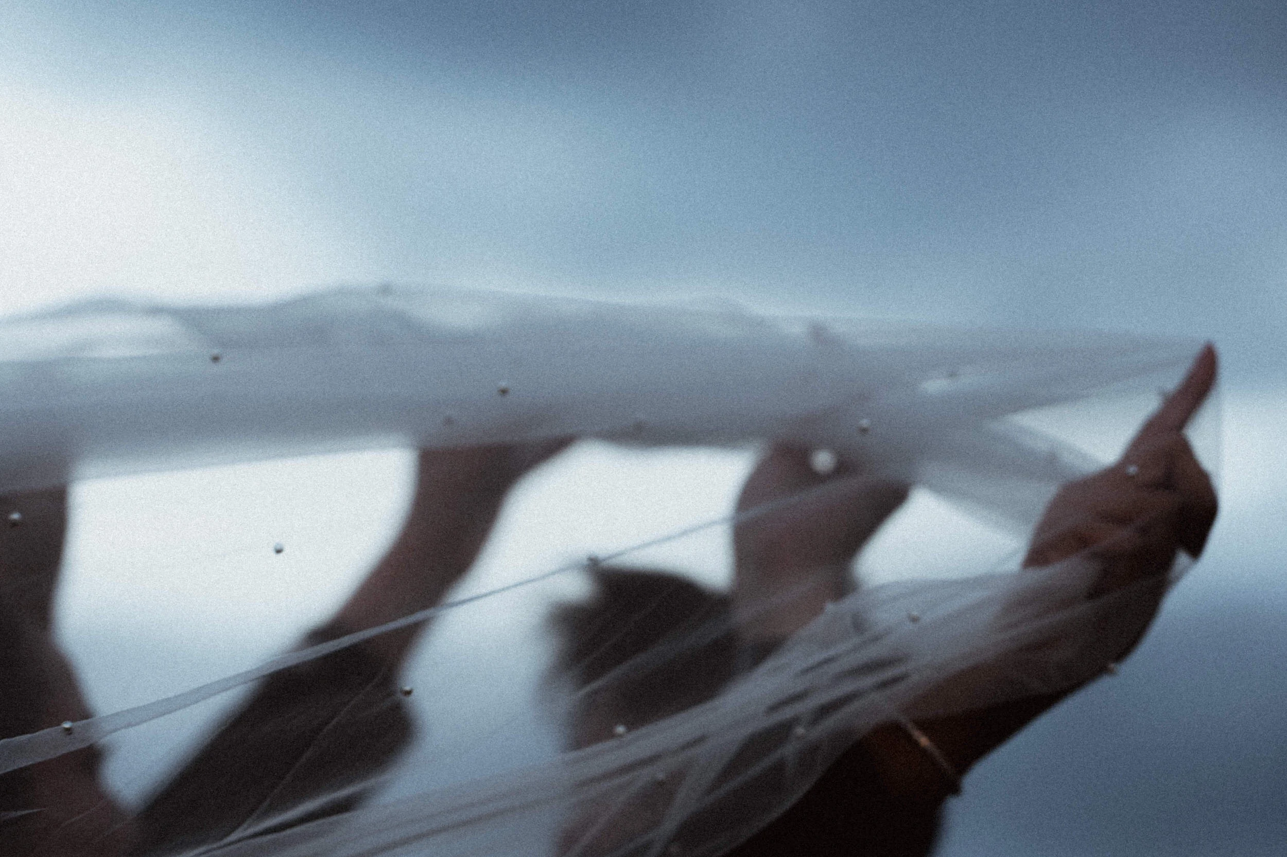 Couple holding a wedding veil abstract closeup photo against an overcast sky