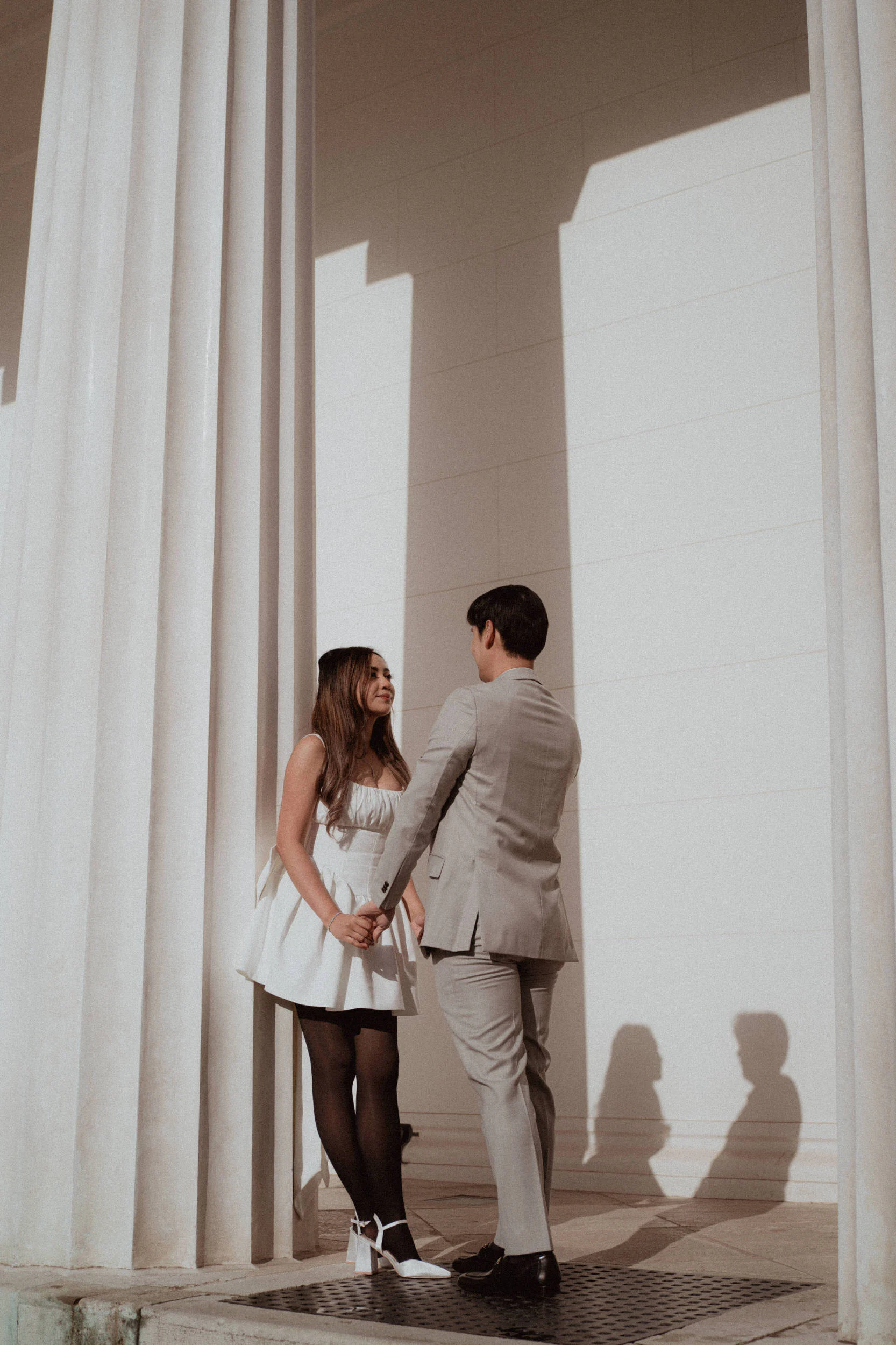 Couple standing holding hands under a column of a theseus temple in Volksgarten