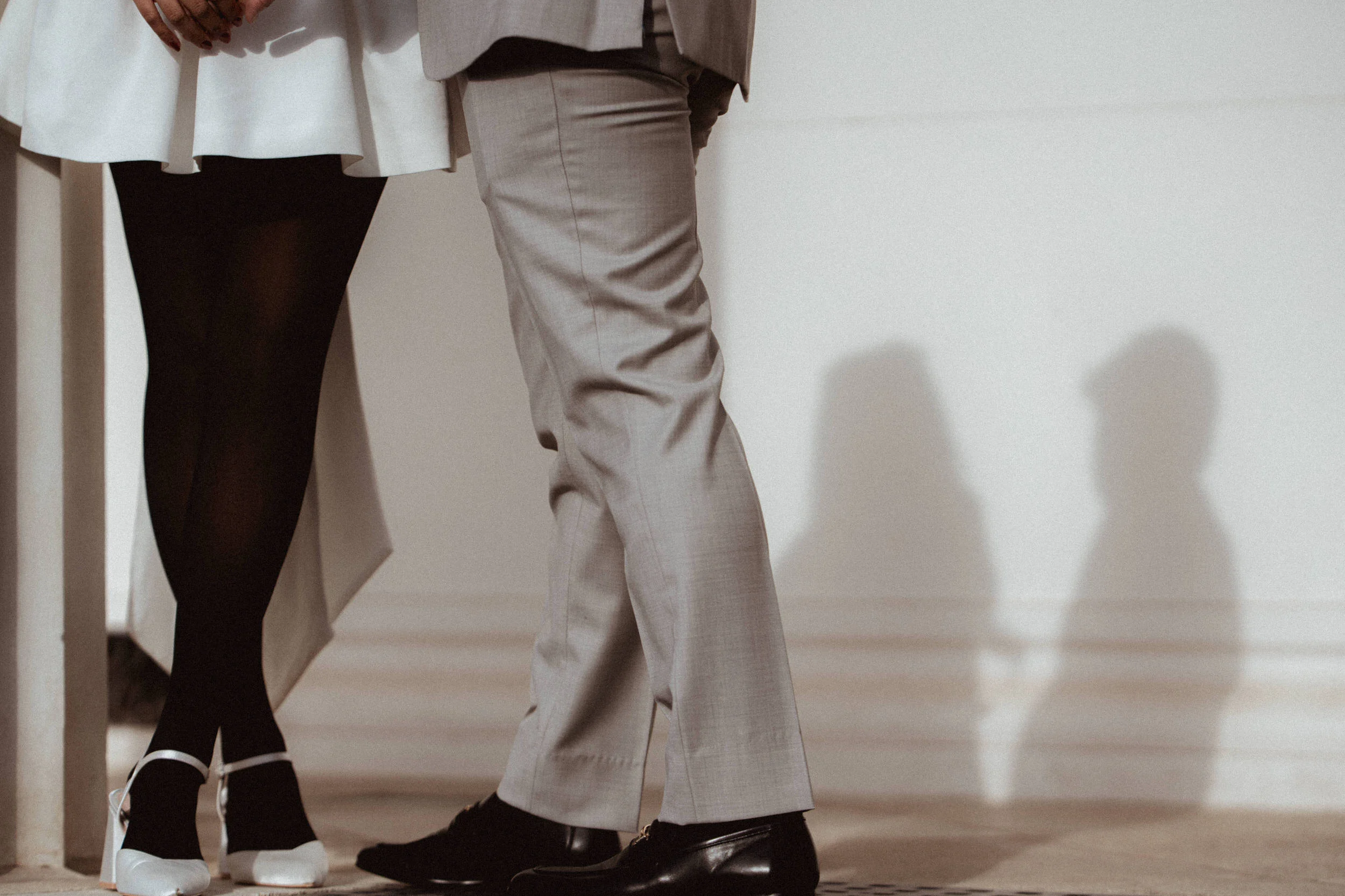 Closeup feet of a couple dancing and their shadow on a white wall