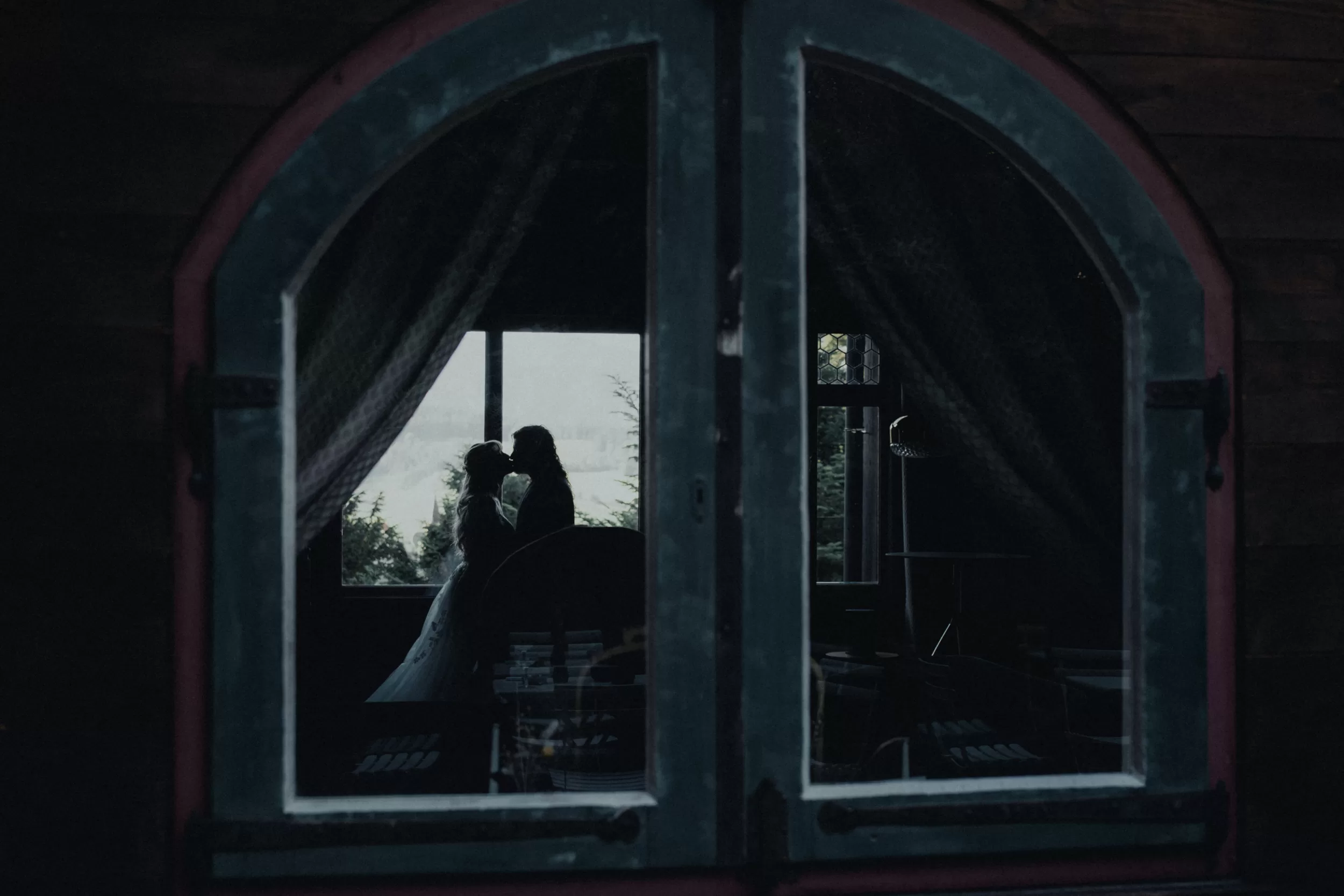 Wedding photoshoot in Austrian alps a couple standing by a window in a villa