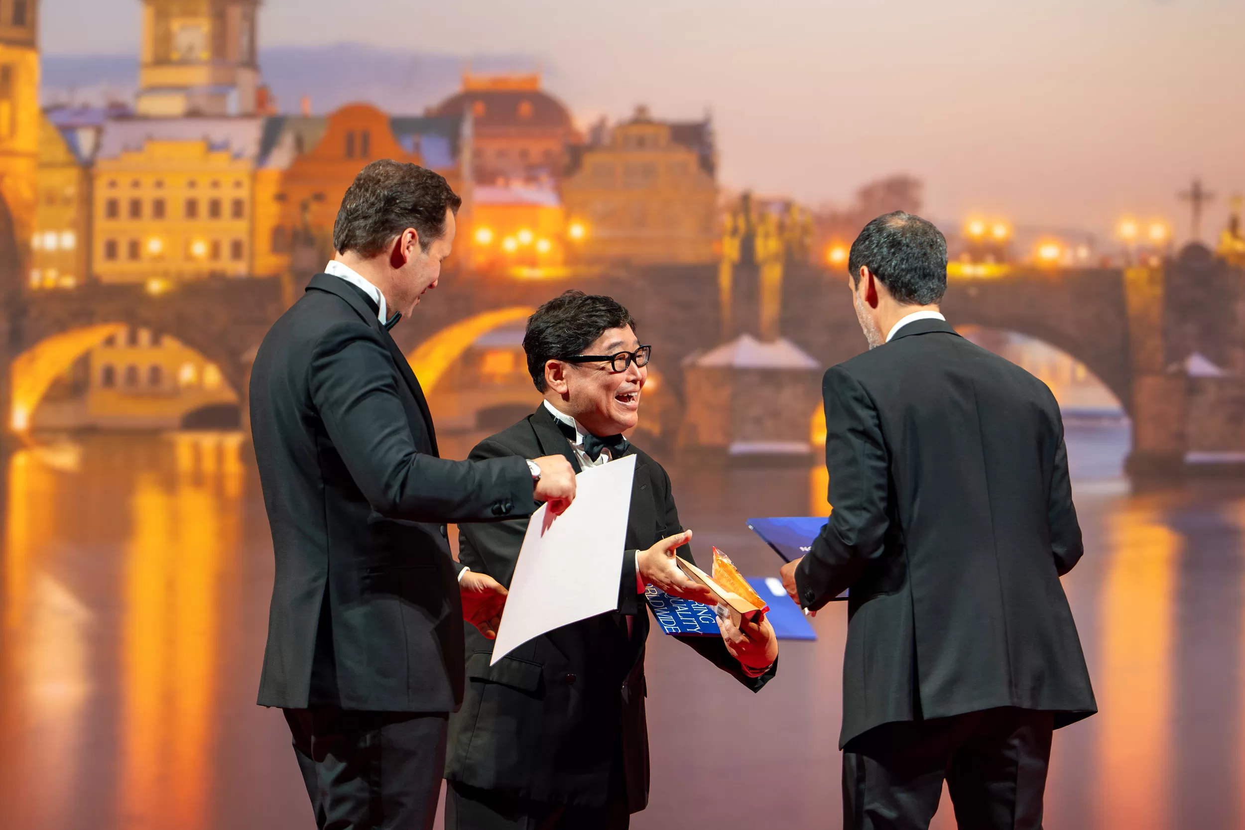 A men exchanging handshakes on a stage of an award ceremony