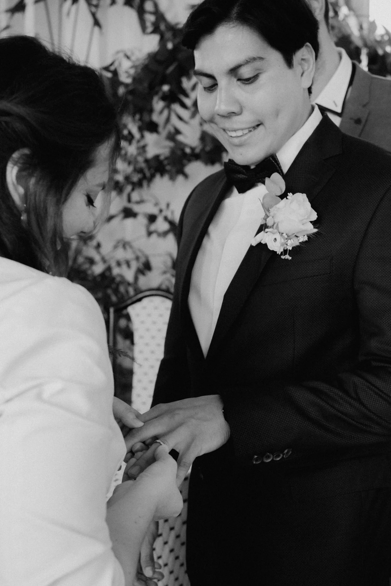 Bride placing a ring on grooms hand, black and white photo