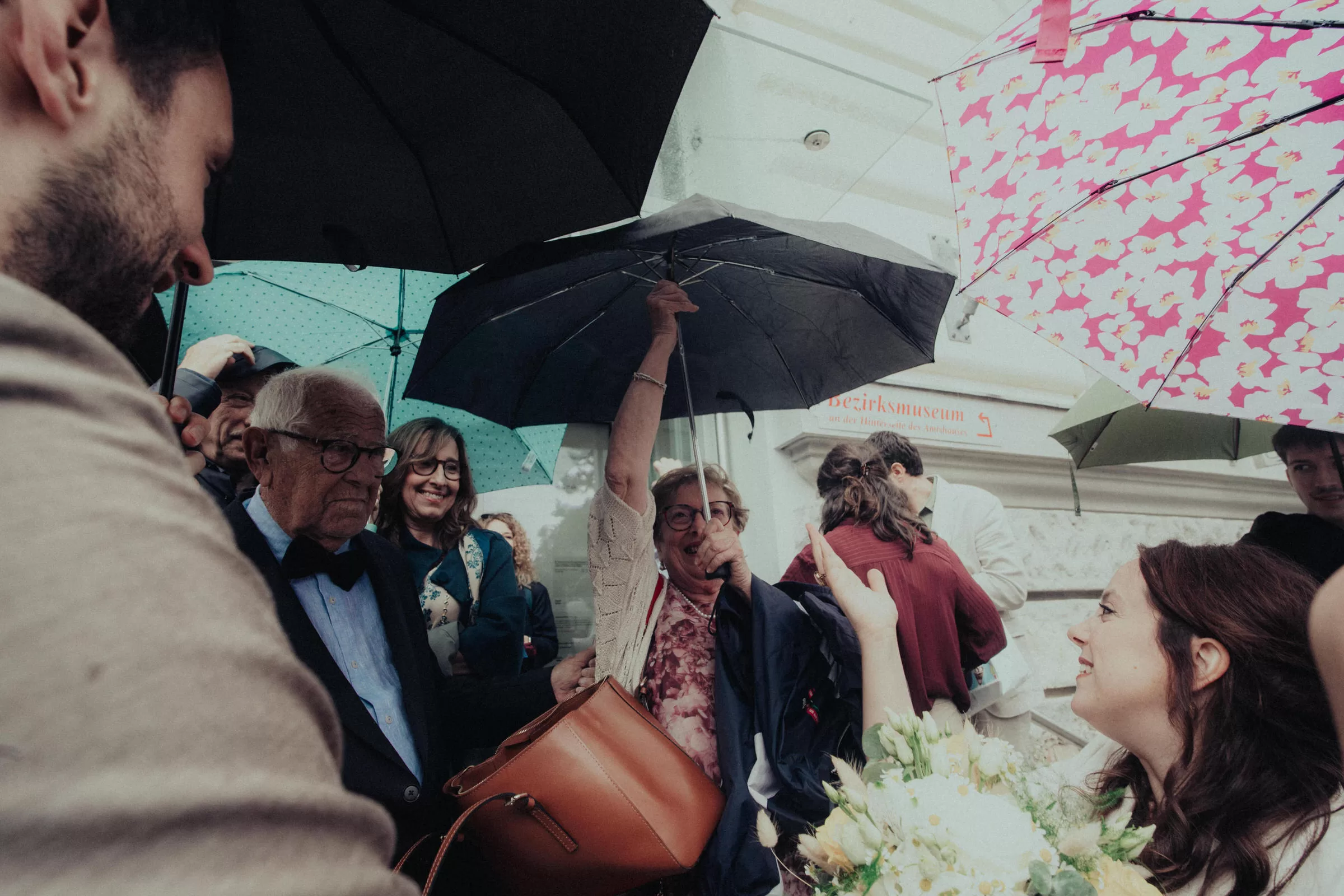 Wedding guests under umbrellas on a wedding day in front of a registry office