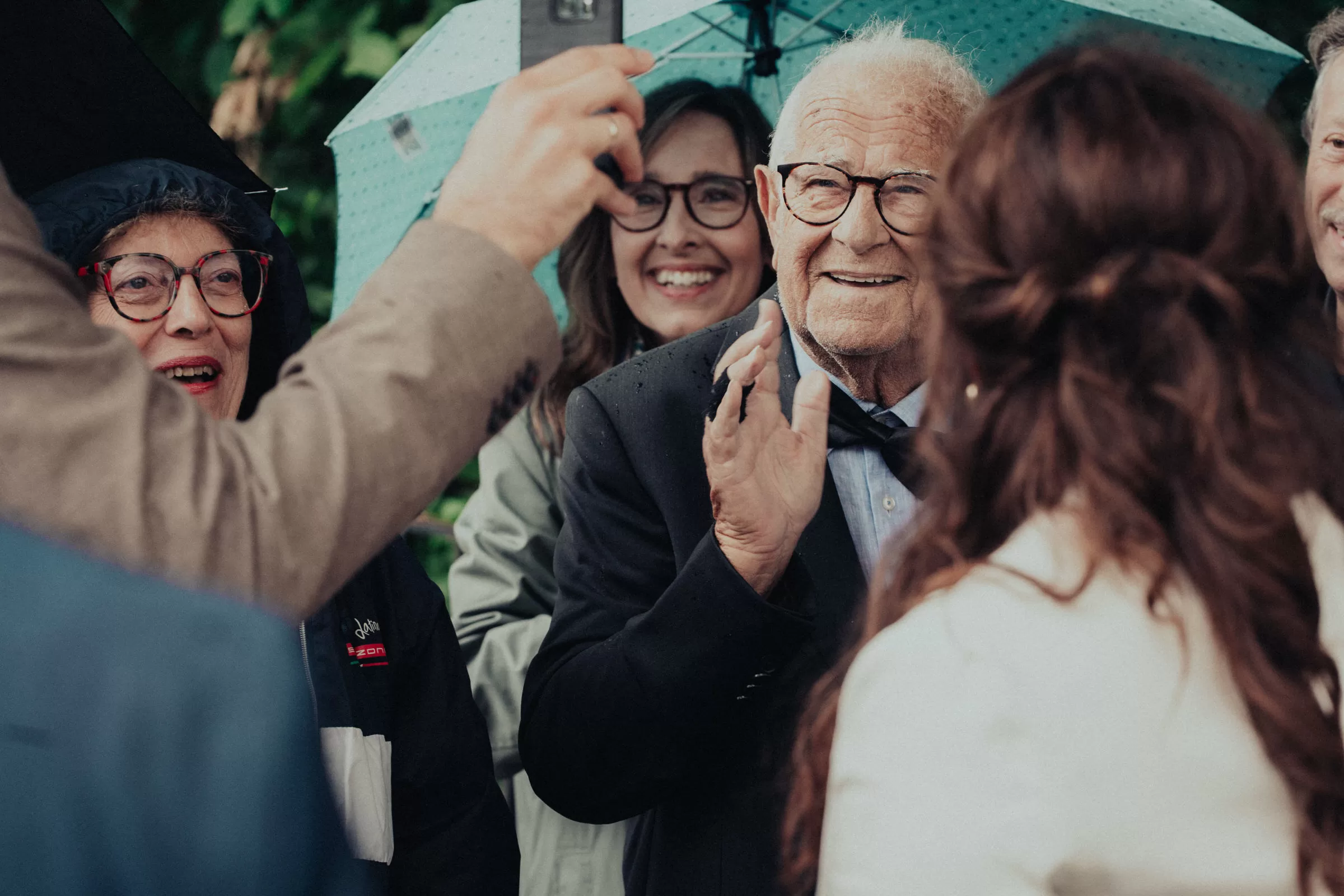Guests of a wedding under umbrellas after a ceremony