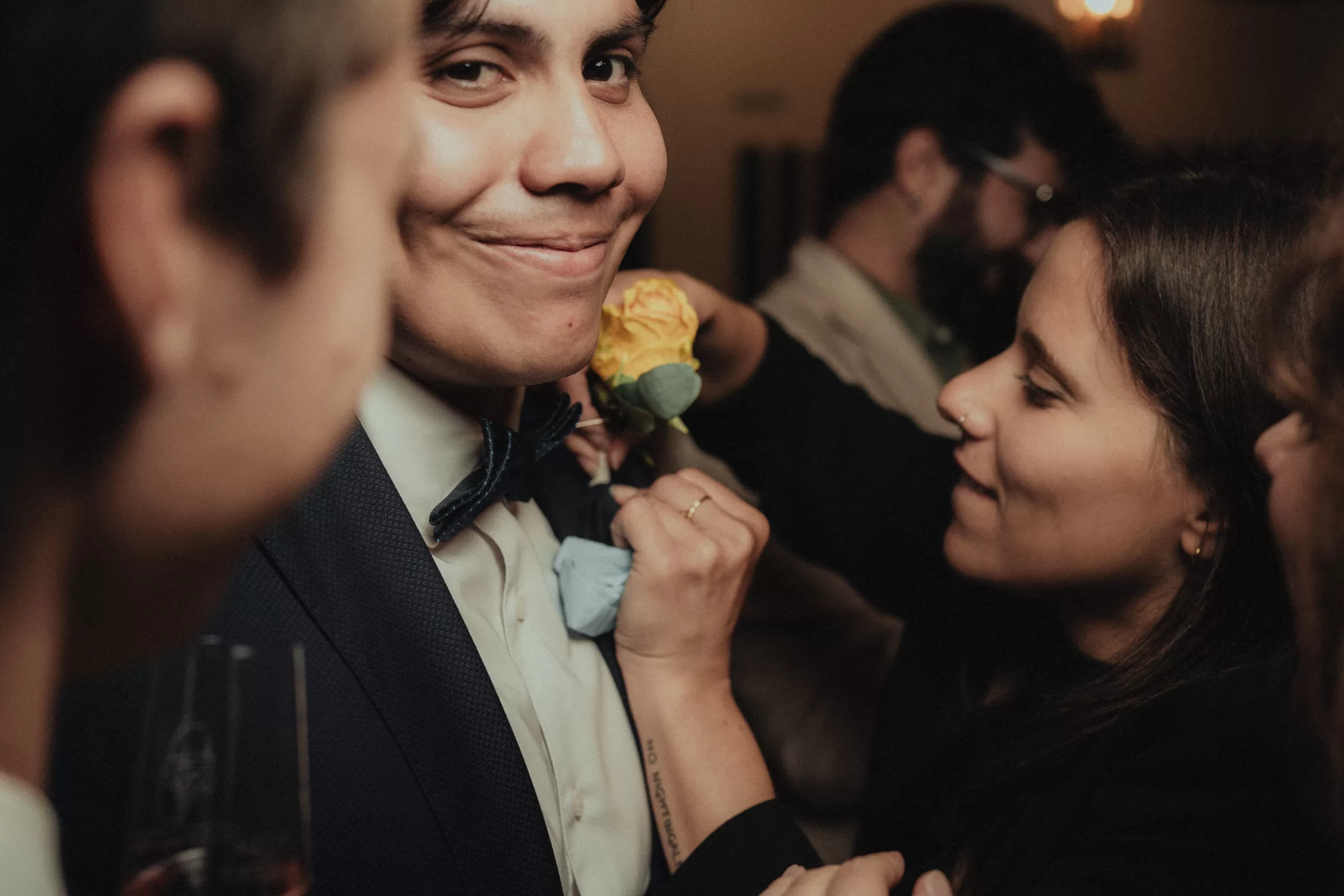 groom with guests on his wedding day fixing a flower on his suit