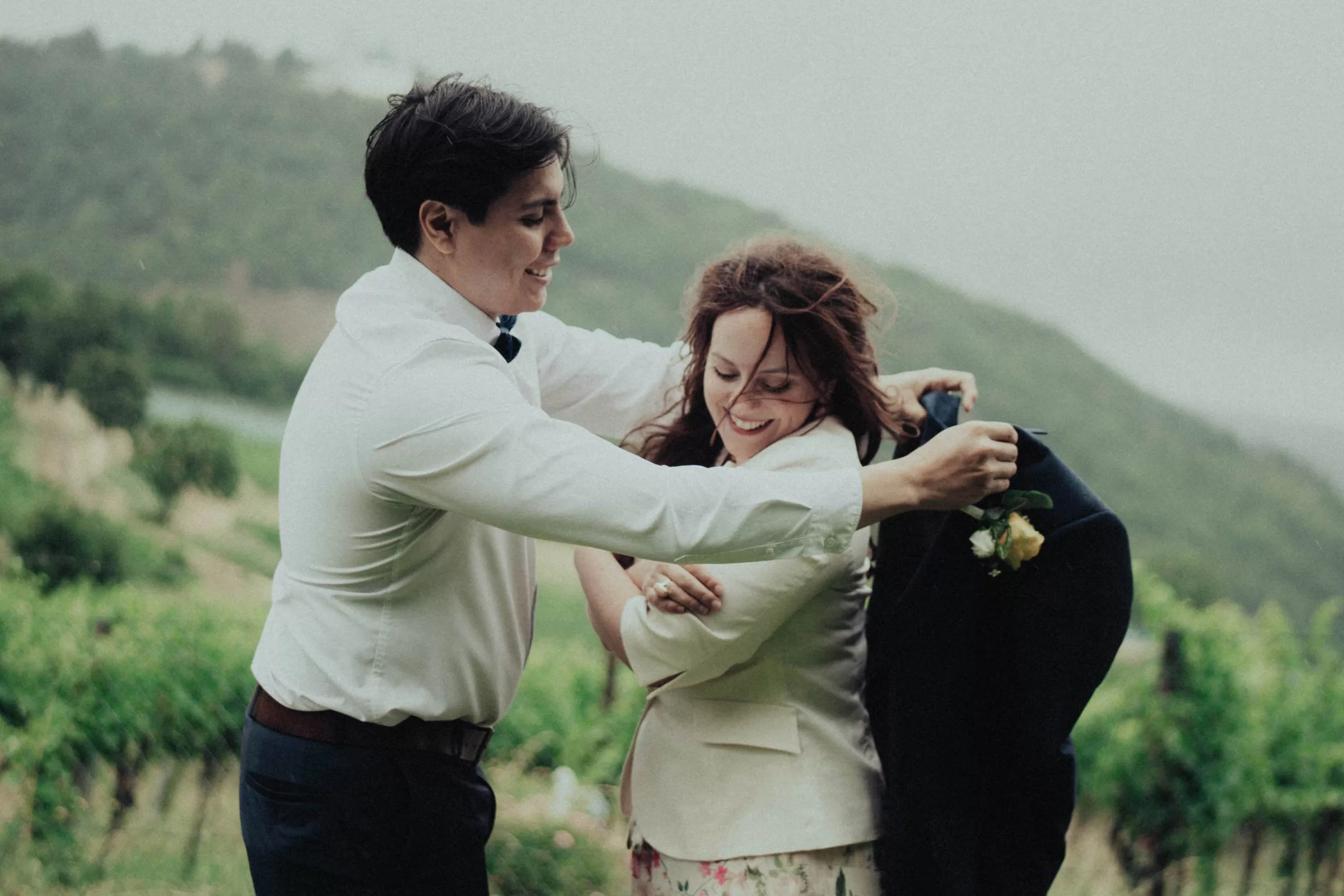 groom puts a jacket over brides shoulders on viennese hills near kahlenberg on a rainy day