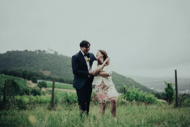 a couple stands in a field on their wedding hugging on a rainy day