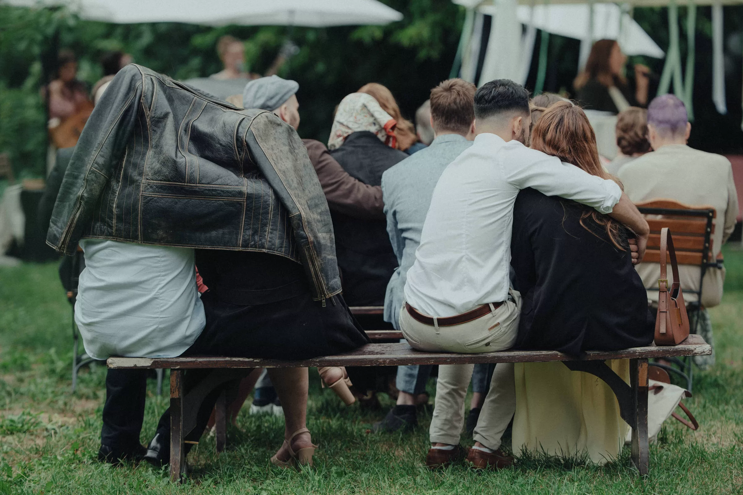 Guests of a wedding hiding from rain under jackets