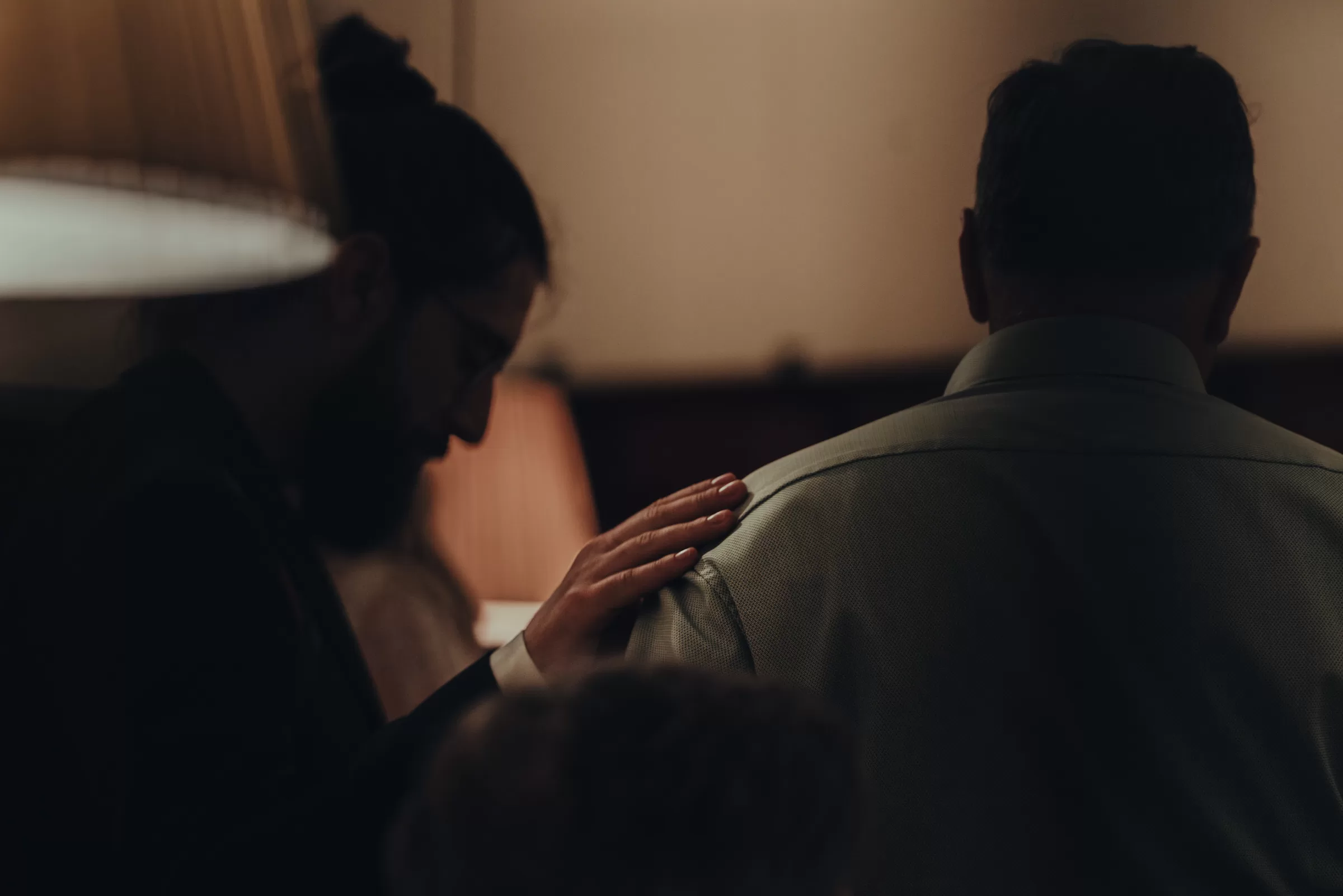 A closeup detail photo of a man putting a hand on a shoulder of anoter man
