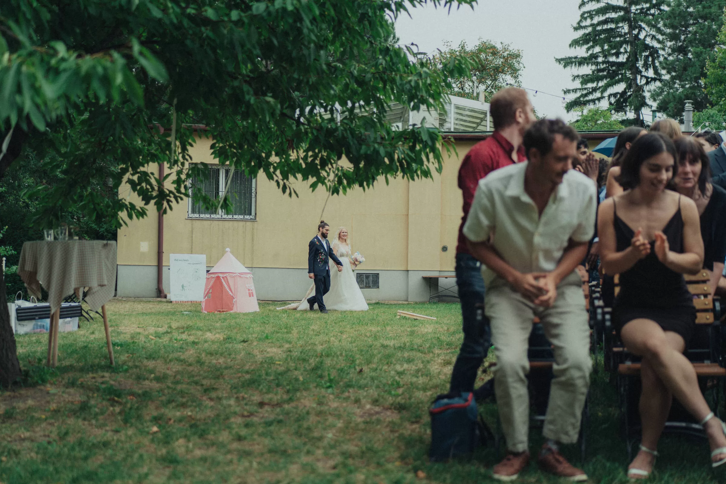 Couple arrives to their garden wedding ceremony and being greeted by the guests