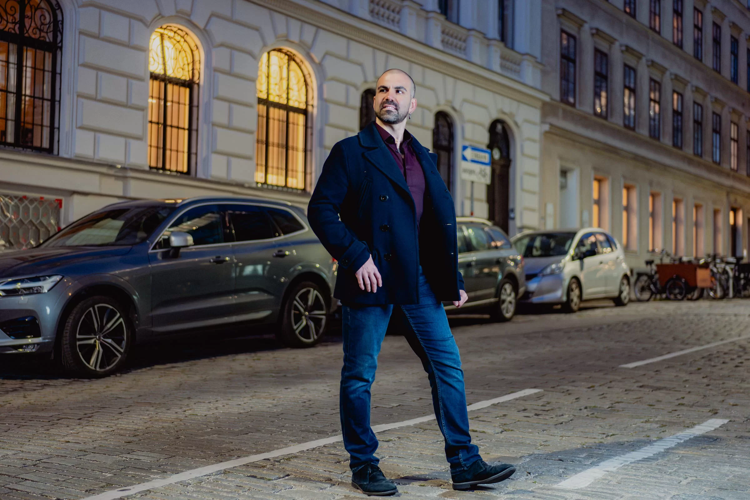A man crossing a street in a dark suit at night