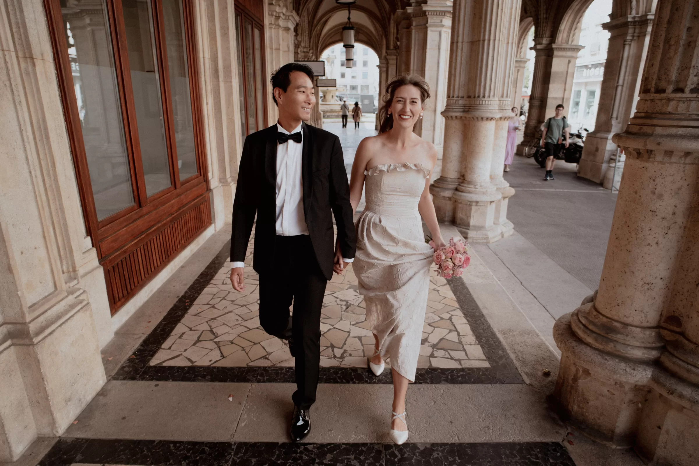Couple running through a gallery with columns along Vienna state opera house