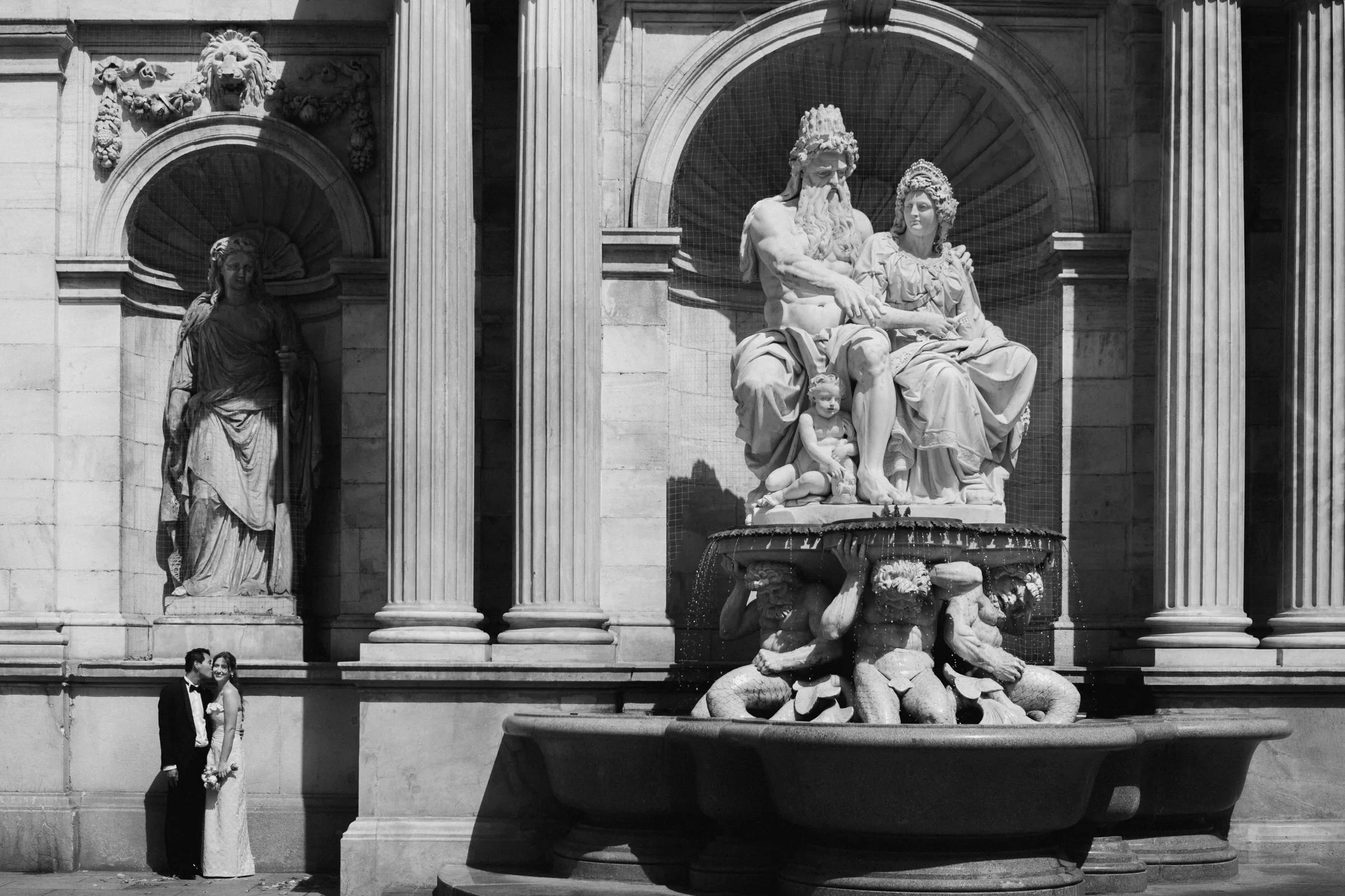 A phot of a couple standing next to a fountain under Albertina terrace in Black and white