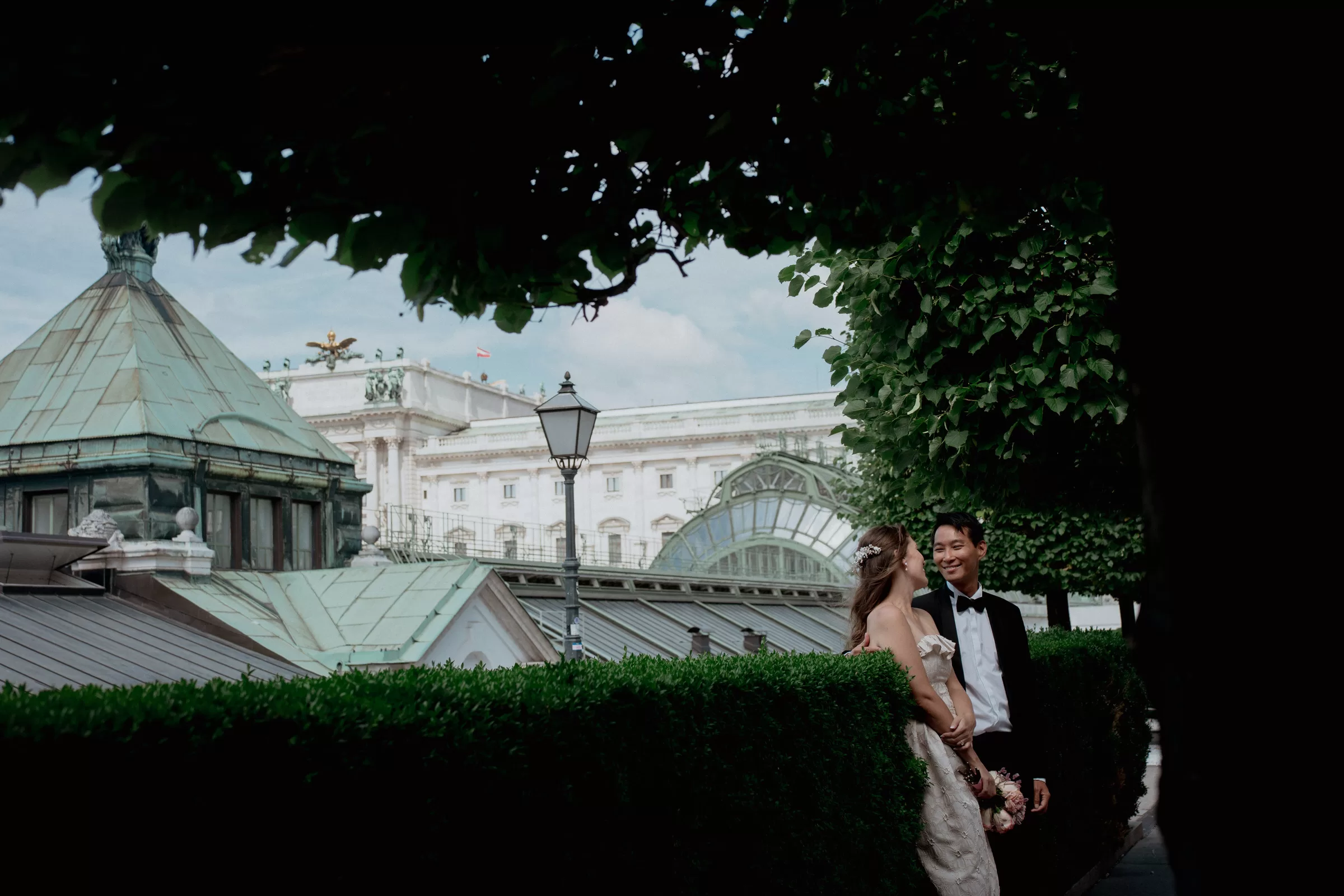 Couple standing next to a hedge on Albertina Terrace with the view on Hofburg