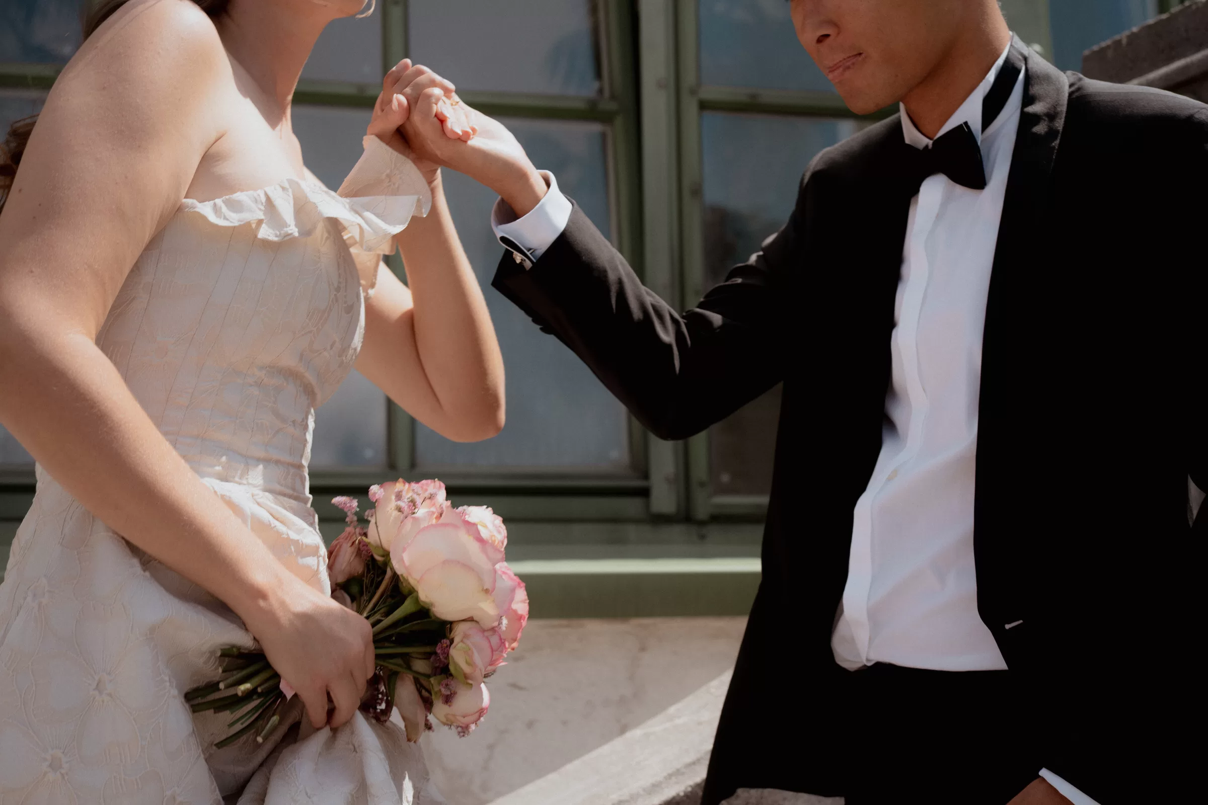 Newlyweds holding hands and the man helps a woman to climb down a big step