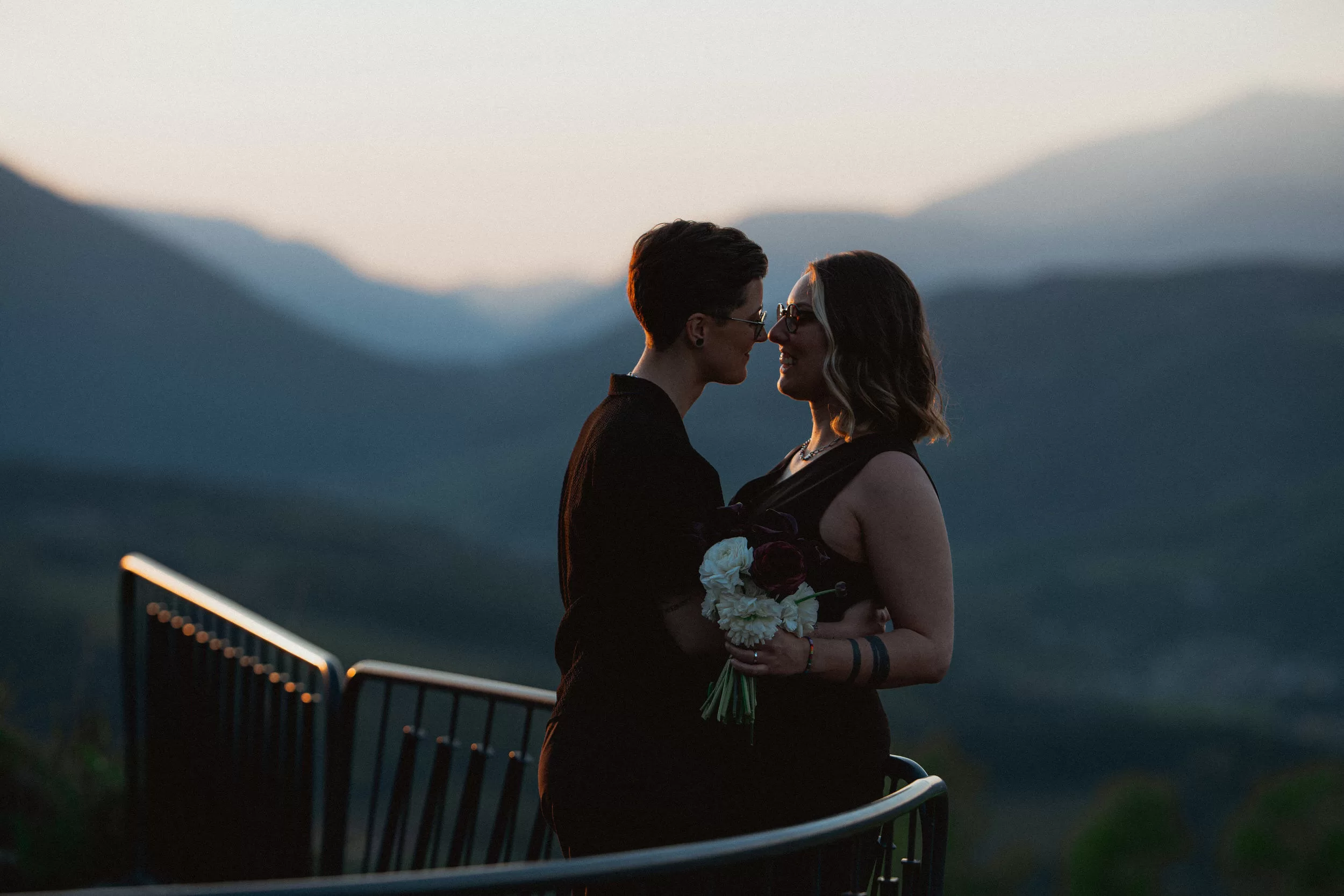 Wedding photo of brides on a terrace of Fernblick hotel with the view over the mountains after sunset