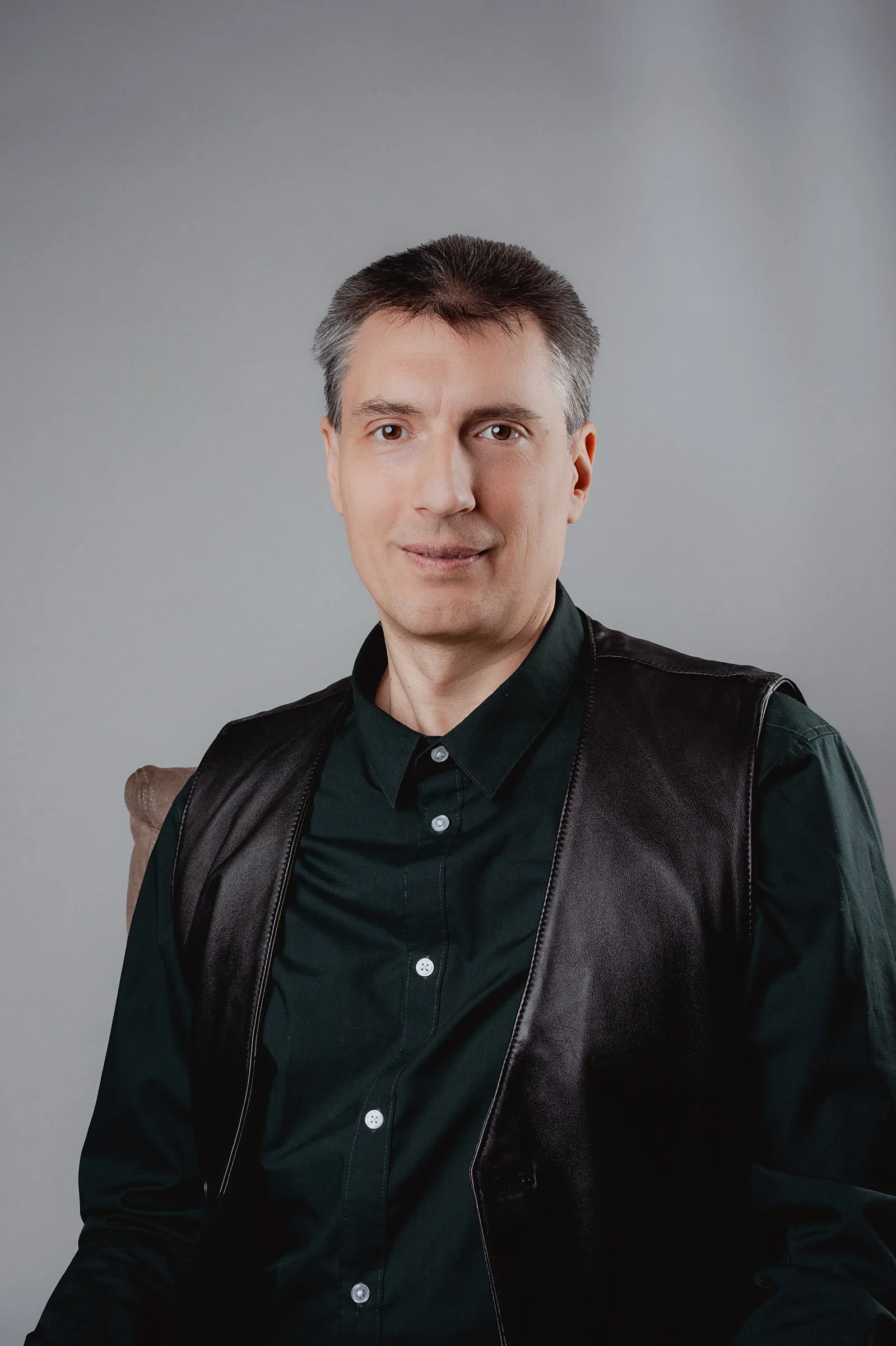 Professional portrait of a man with controlled shadows and a neutral grey background.