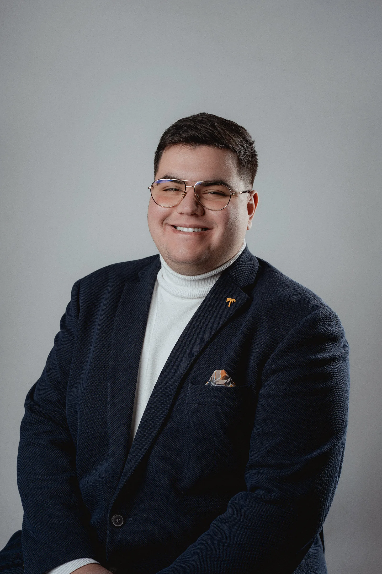 Consistent business portrait of a man smiling in a classic suit in front of a light grey background
