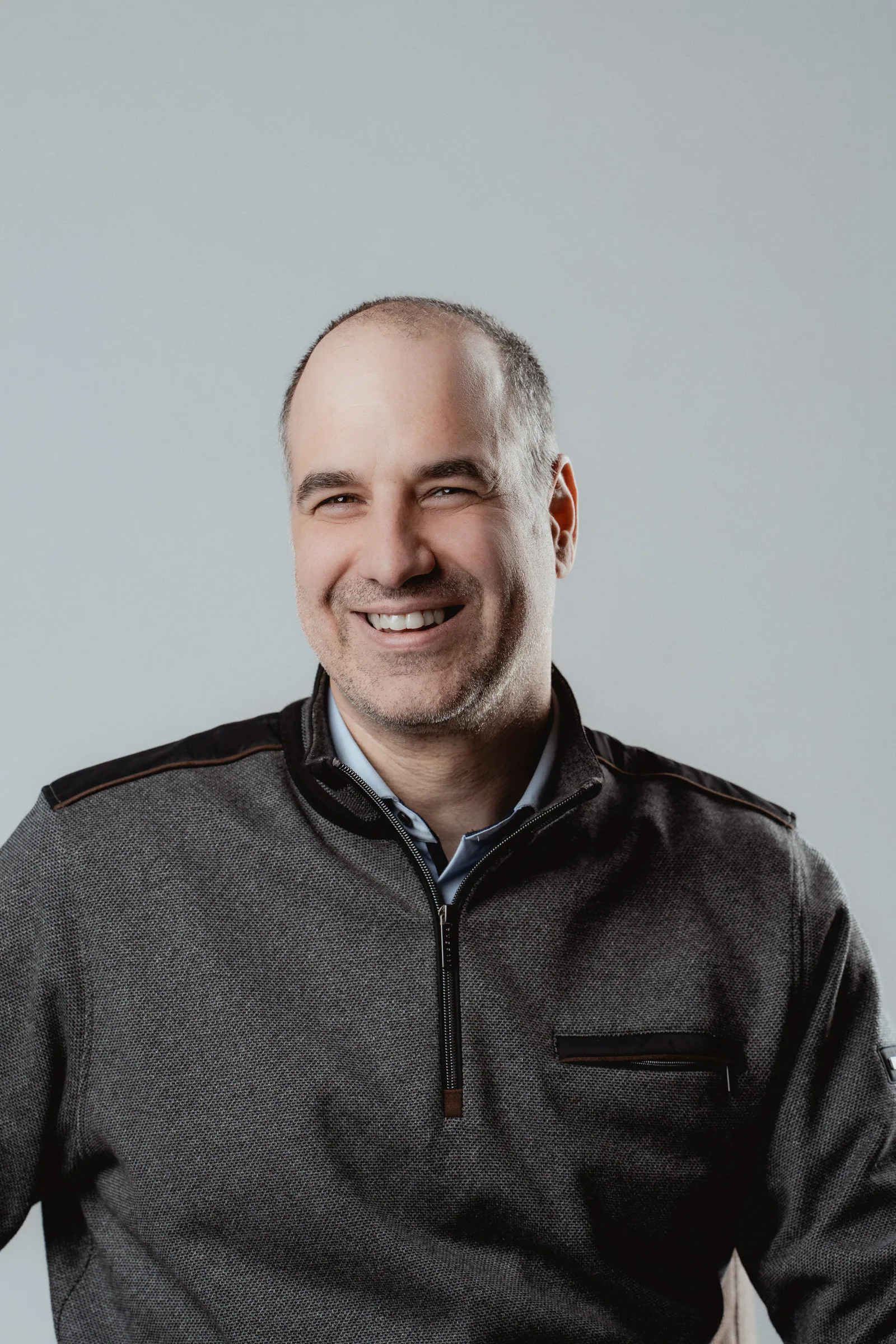 Clean, modern business portrait with a grey studio backdrop.