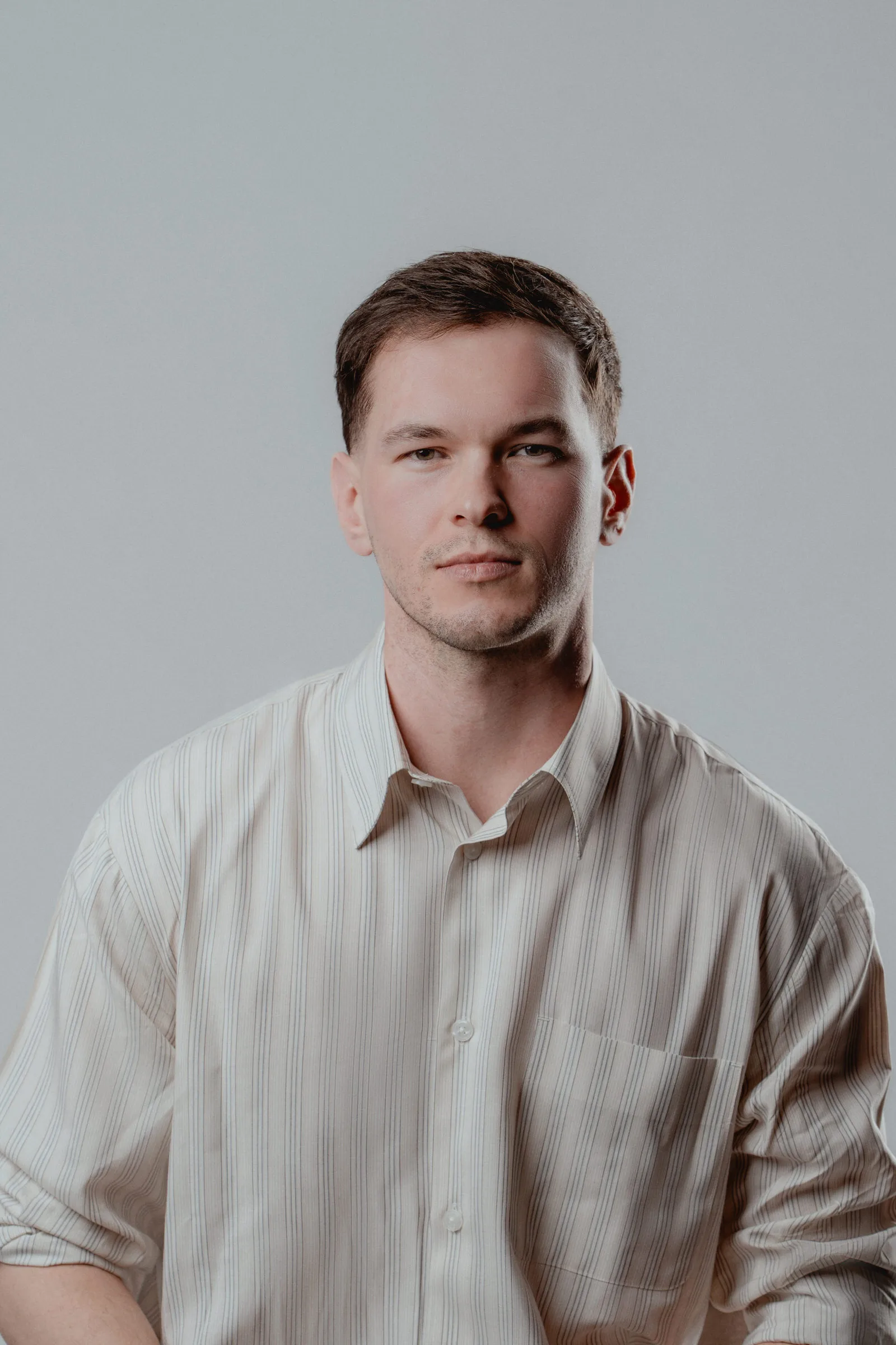 Male portrait with a neutral grey background, taken in a Vienna studio.