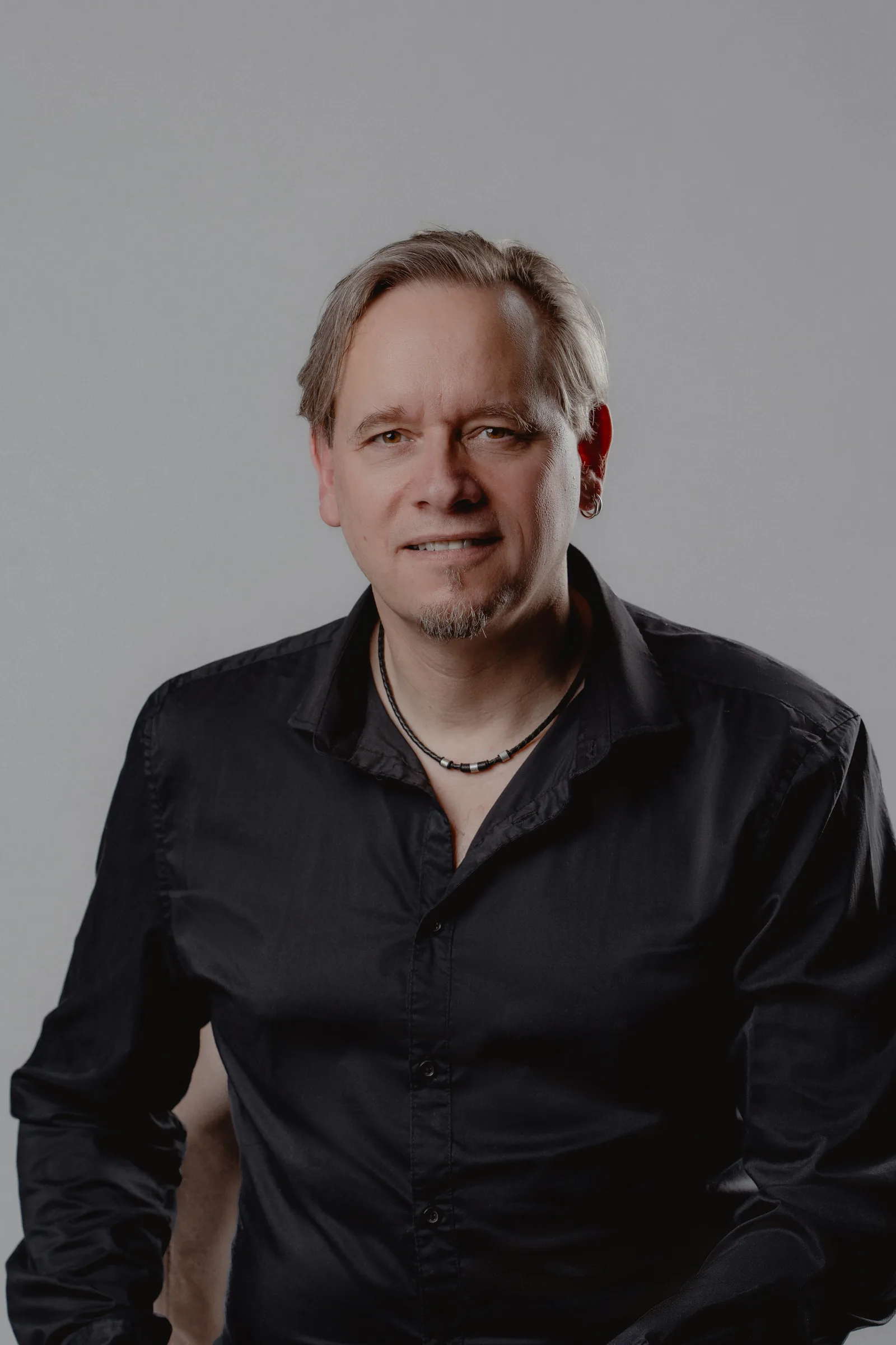 Modern corporate headshot of a man, soft grey backdrop and a polished look.