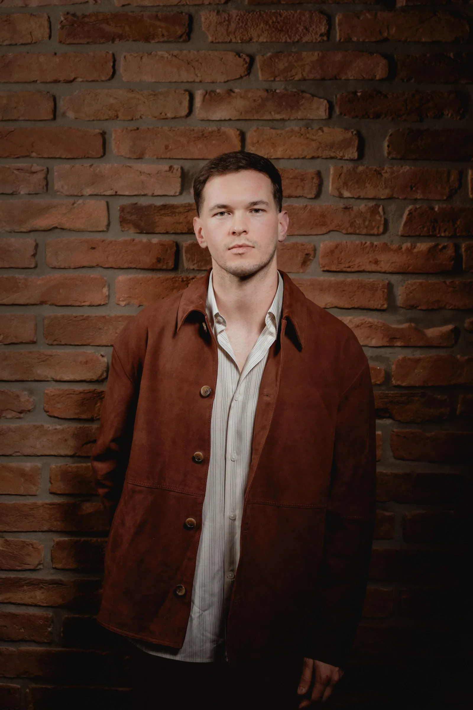 Portrait of a man in front of a brick wall by portrait photographer in Vienna Fedor Vasilev