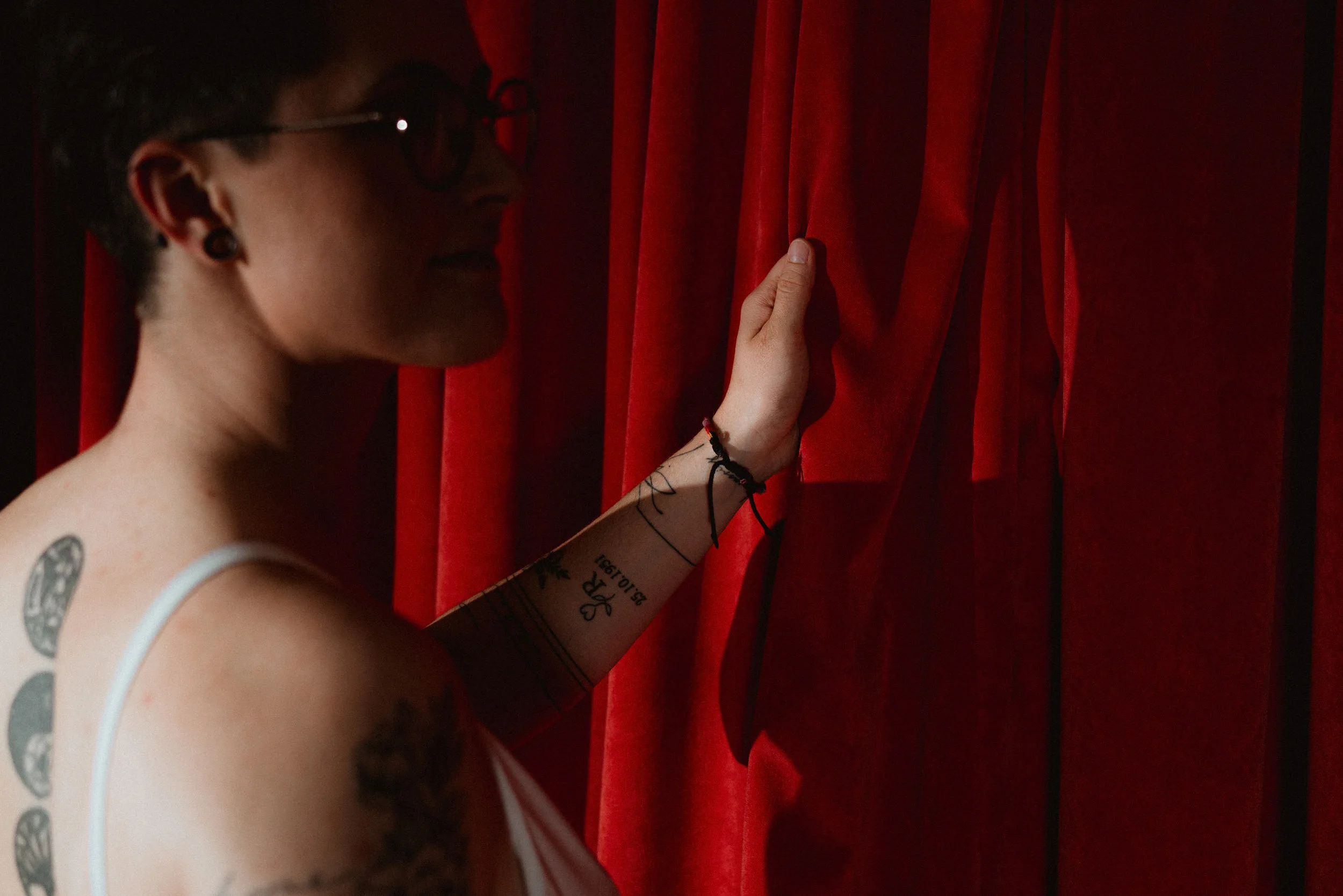 Portrait of a bride holding a red curtain and looking to a side with dramatic light in cinematic style