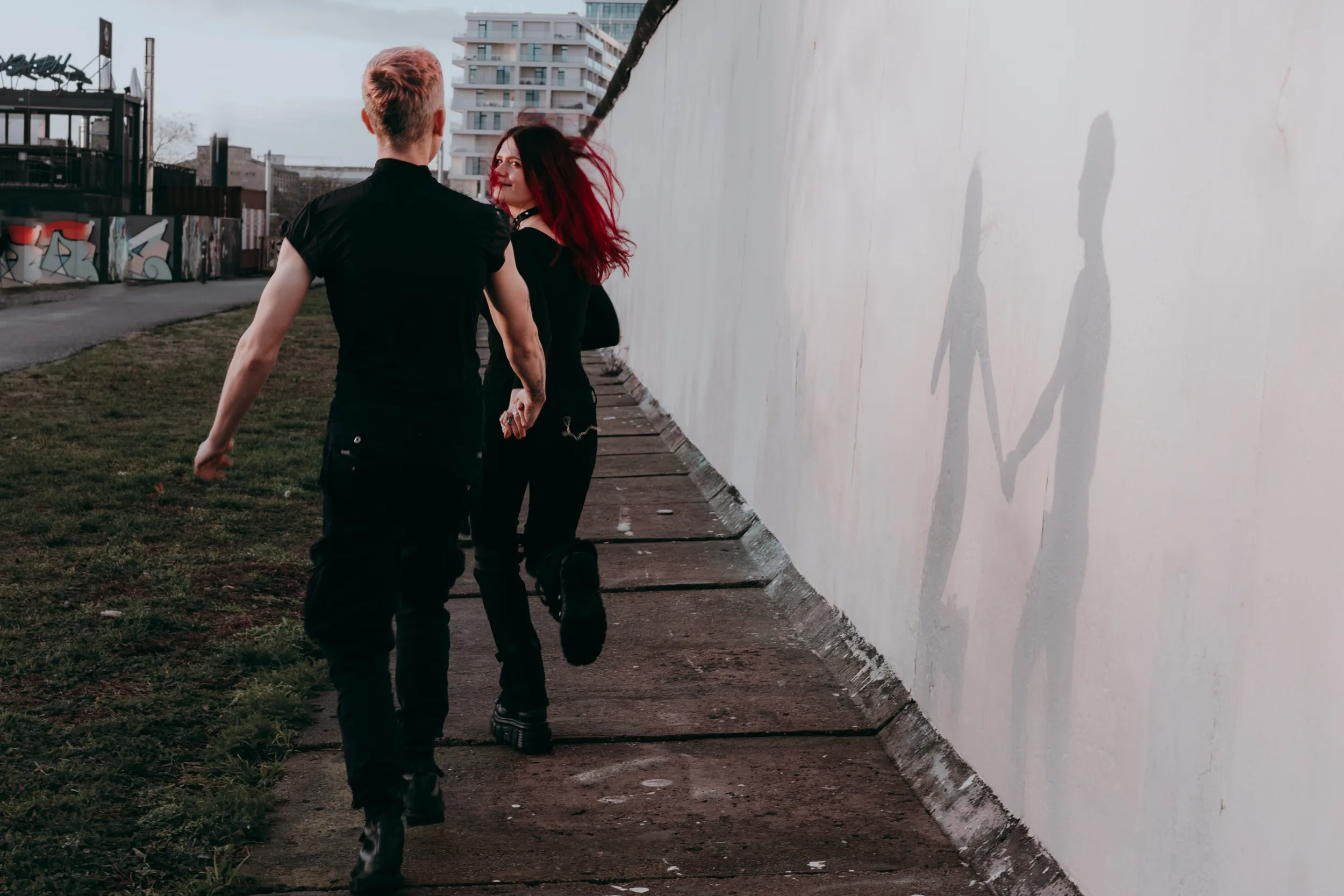A couple running along Berlin wall on a sunny day