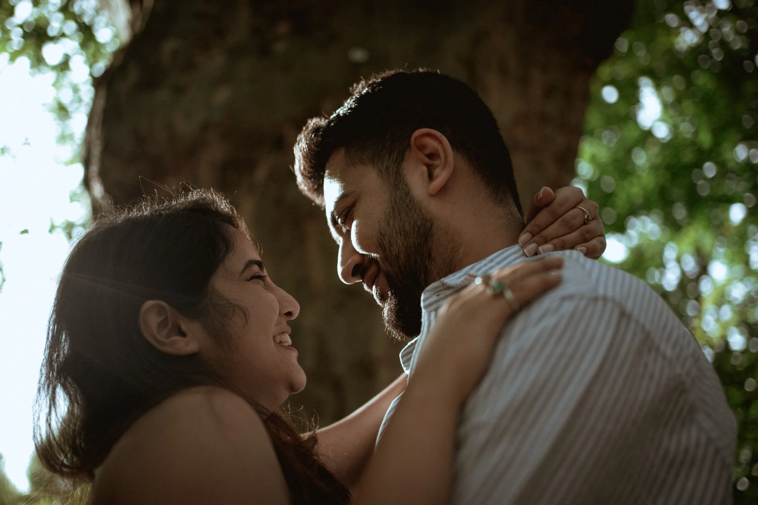 A closeup of a happy couple under a tree on a sunny day