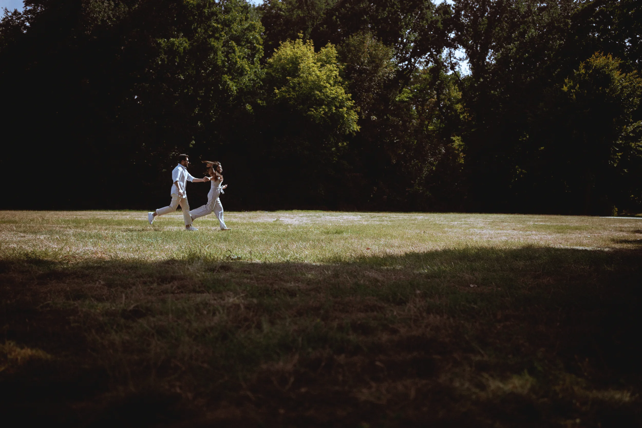 Couple running through a field in Treptower park, engagement photoshoot in Berlin