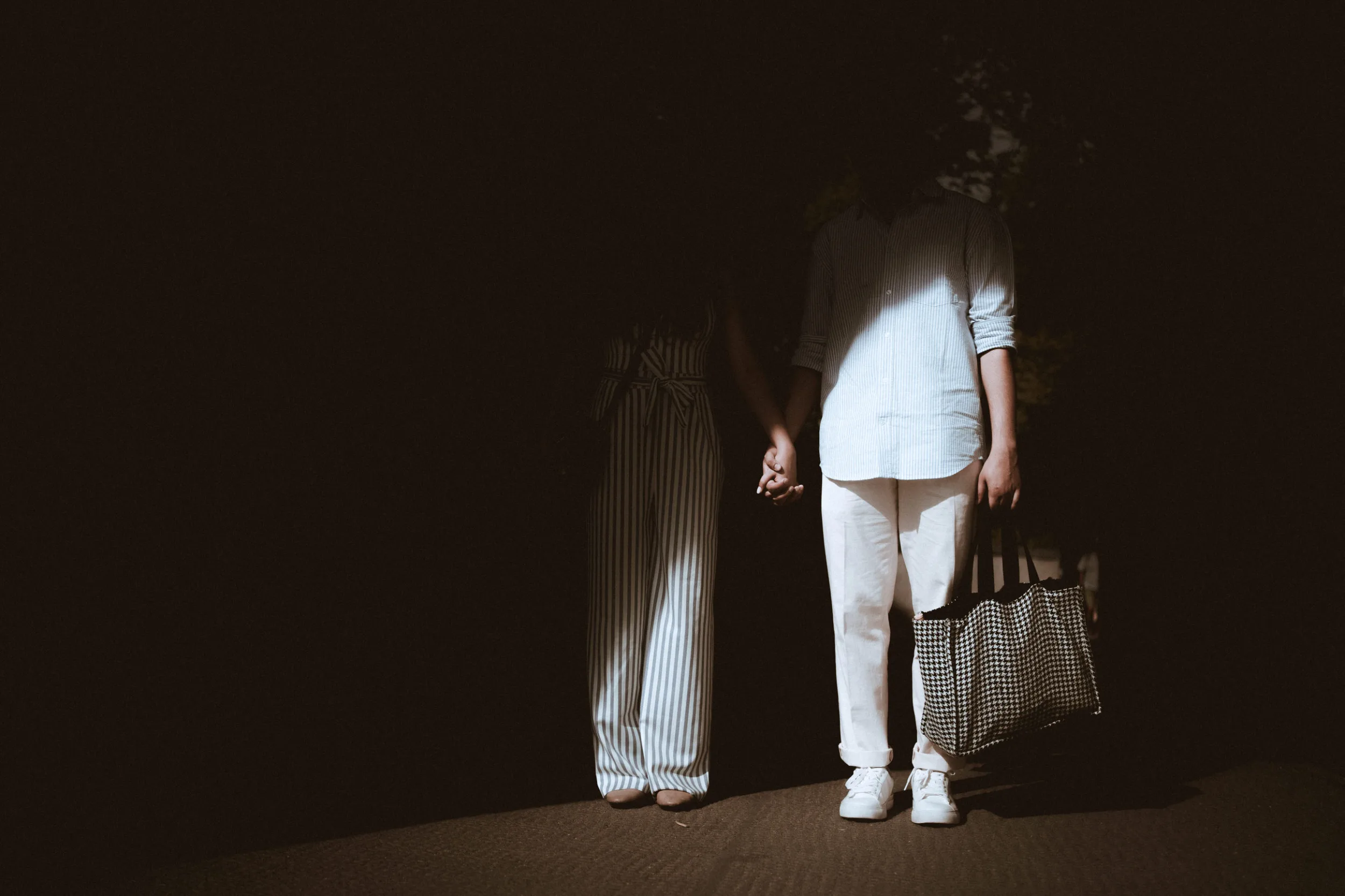 A couple walking out of a shadow under an arc in Berlin