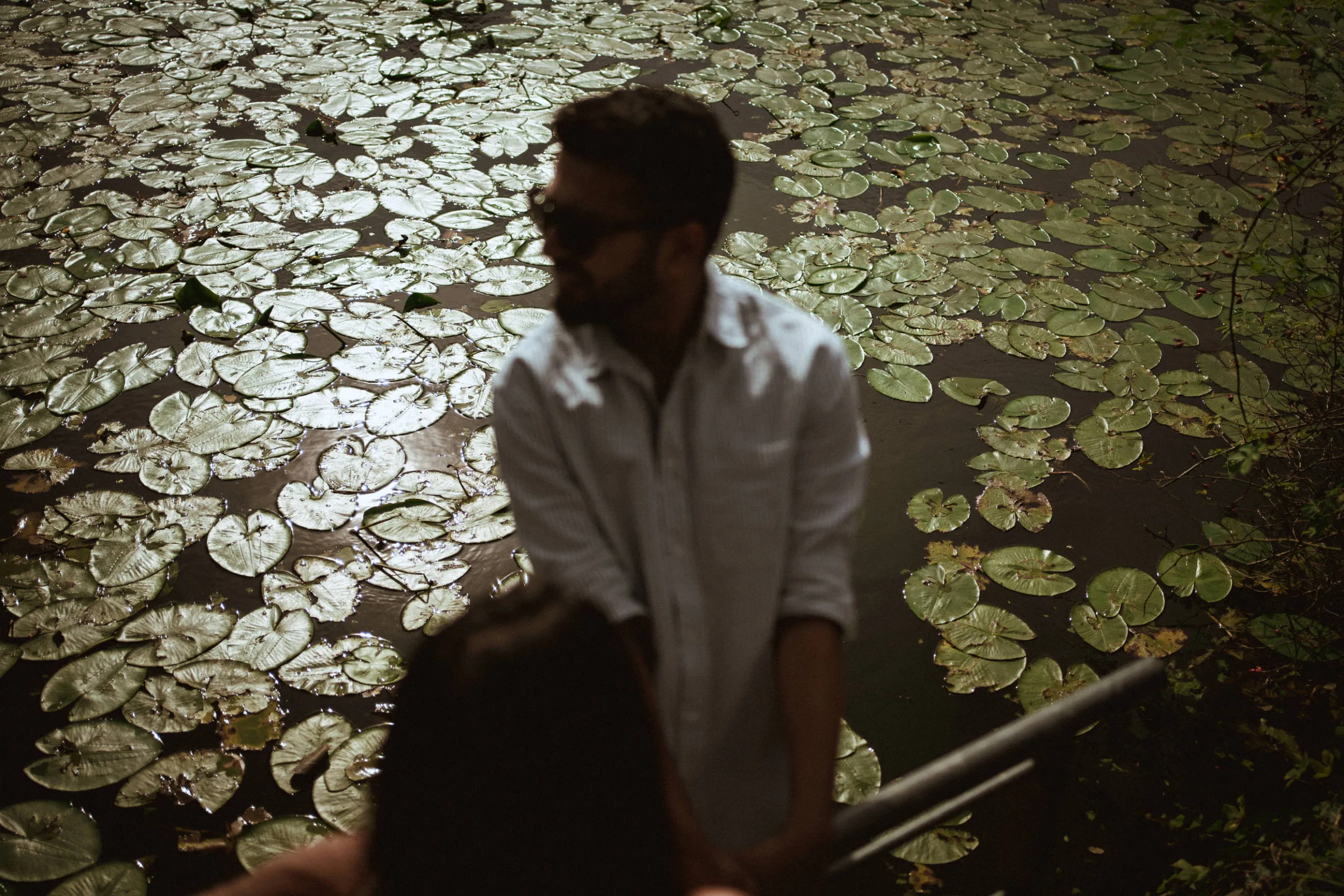 A photo of a couple by the water with lilypods