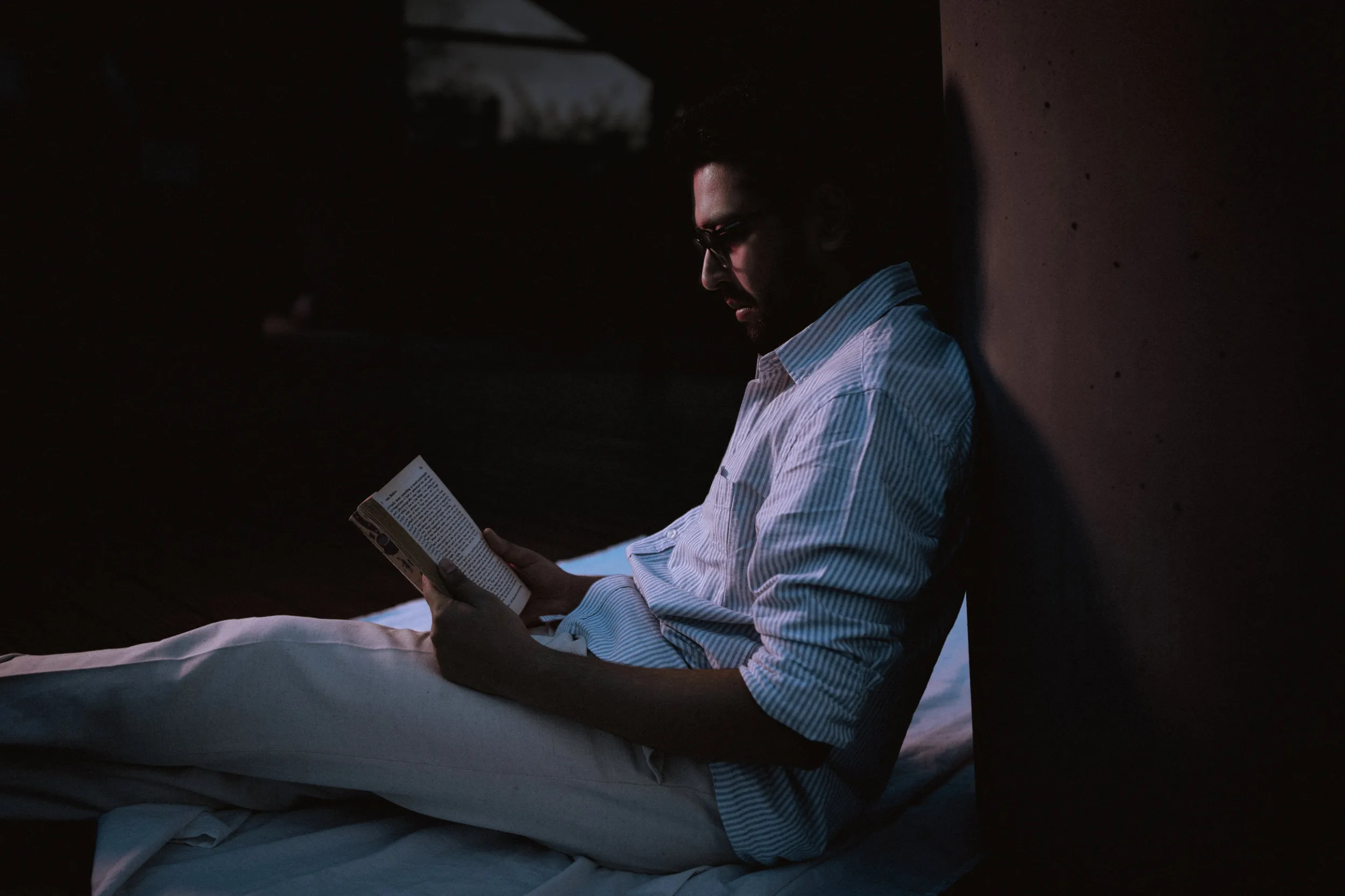 A young man sitting outside in an evening with a book next to Tempodrom in Berlin