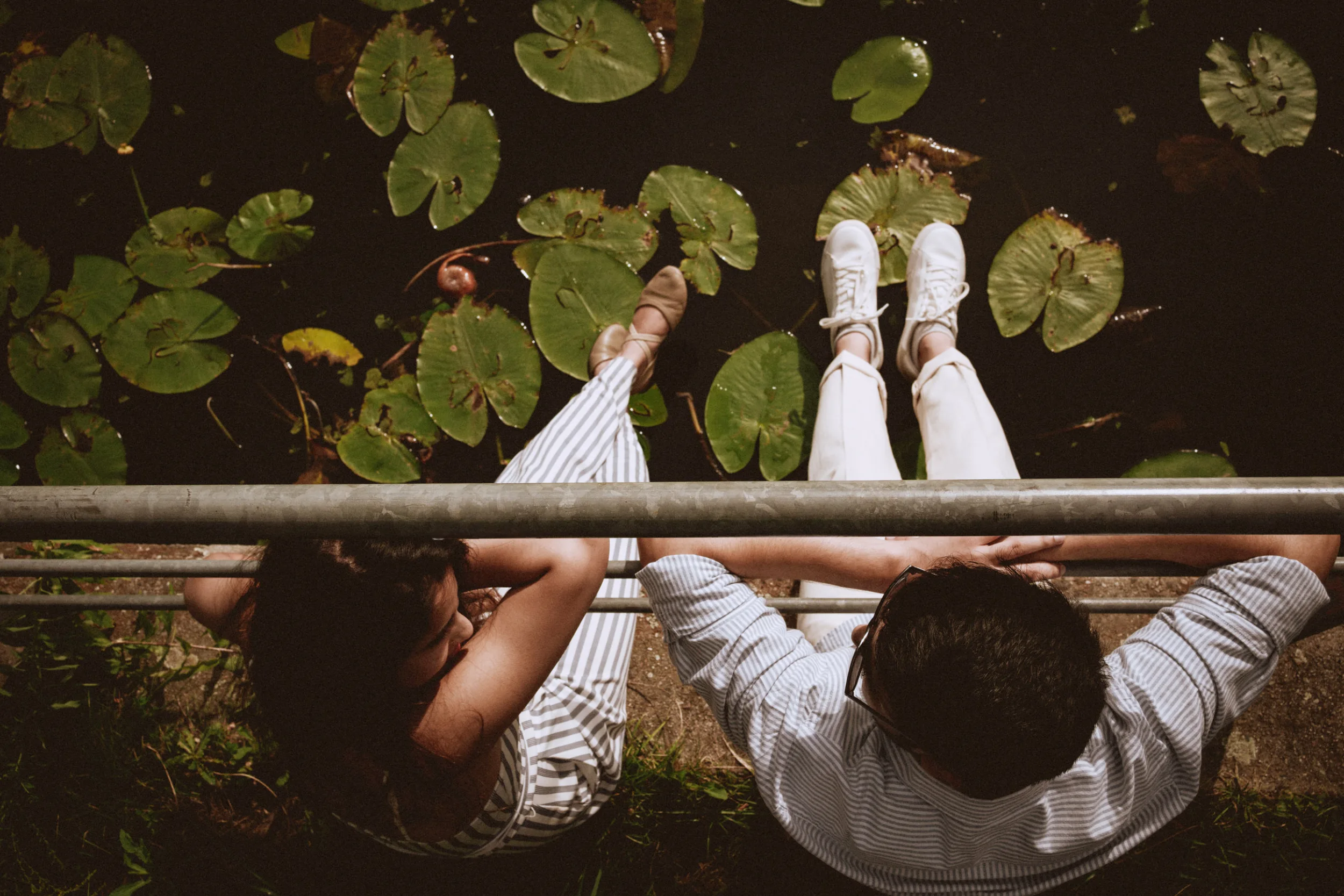 Couple sitting next to Spree on the river bank with lilypods below. Couple photoshoot in Berlin