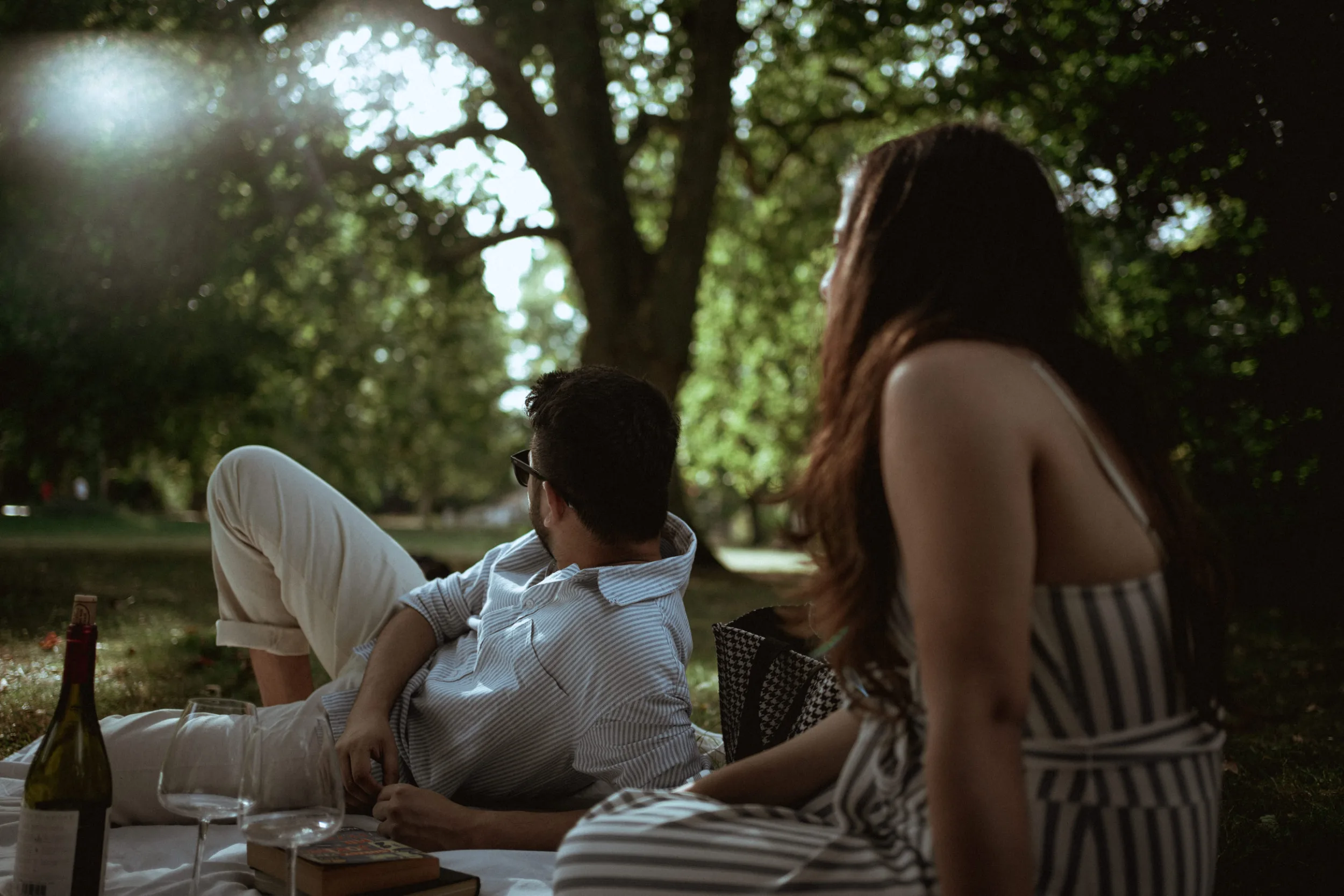 Couple on a picnic in a park on a sunny day; from a romantic engagement photoshoot in Berlin