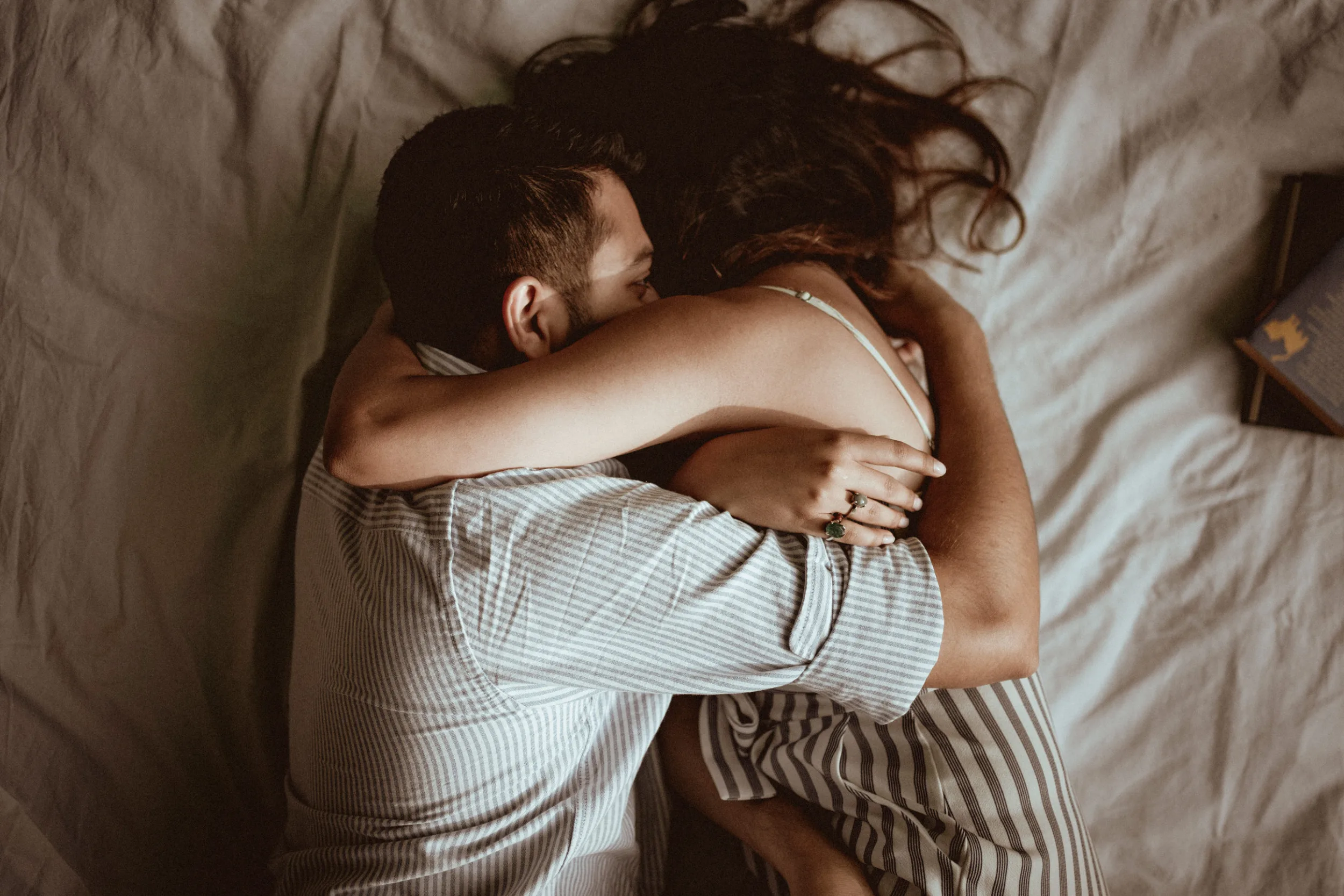 Couple hugging closely laying on a blanket during a picnic in Treptower Park in Berlin