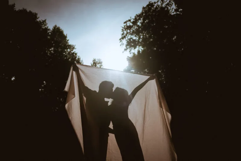 A dramatic photo of a couple kissing behind a blanket in Treptower park in Berlin