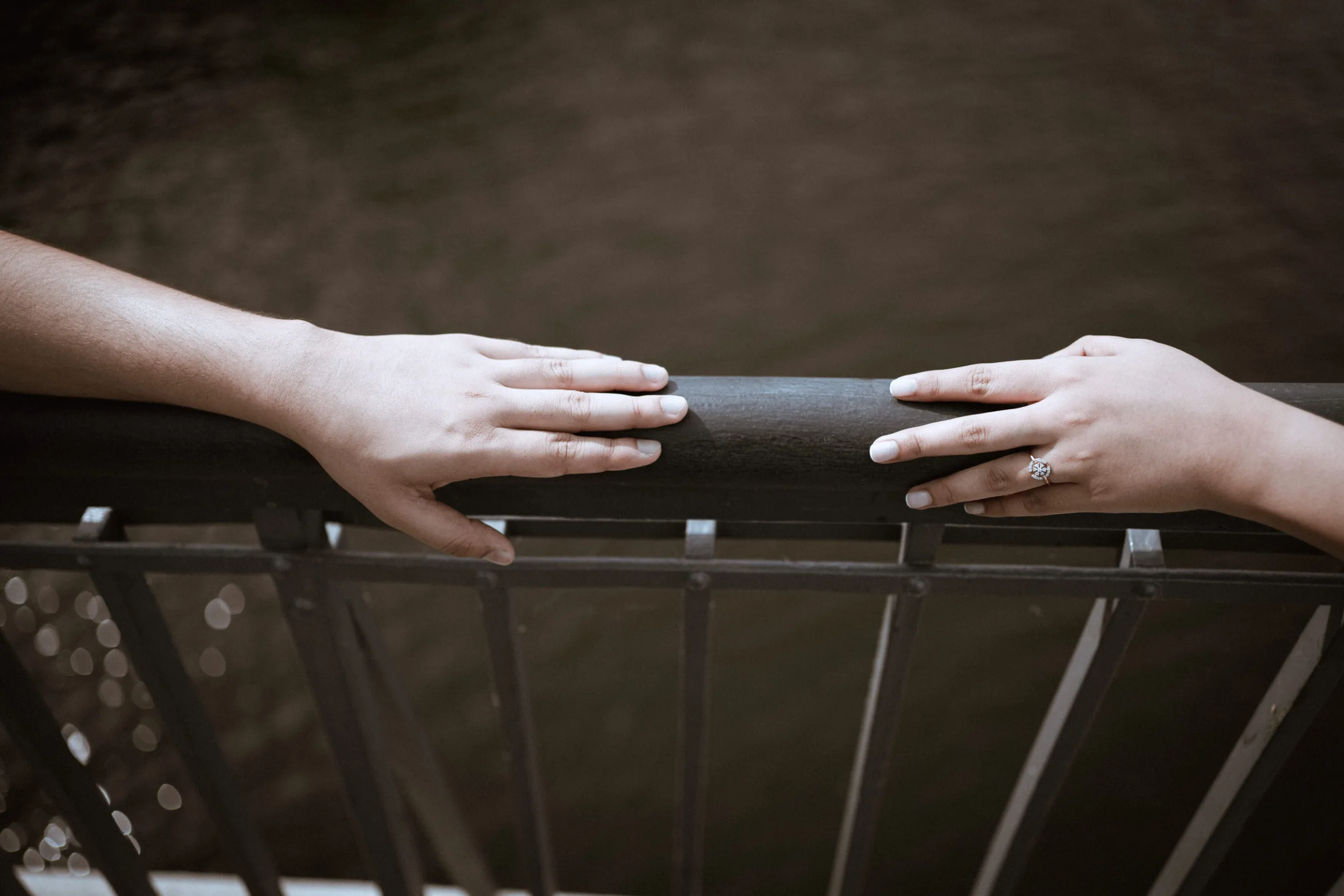 Closeup detail of hands on a bridge reaching to each other
