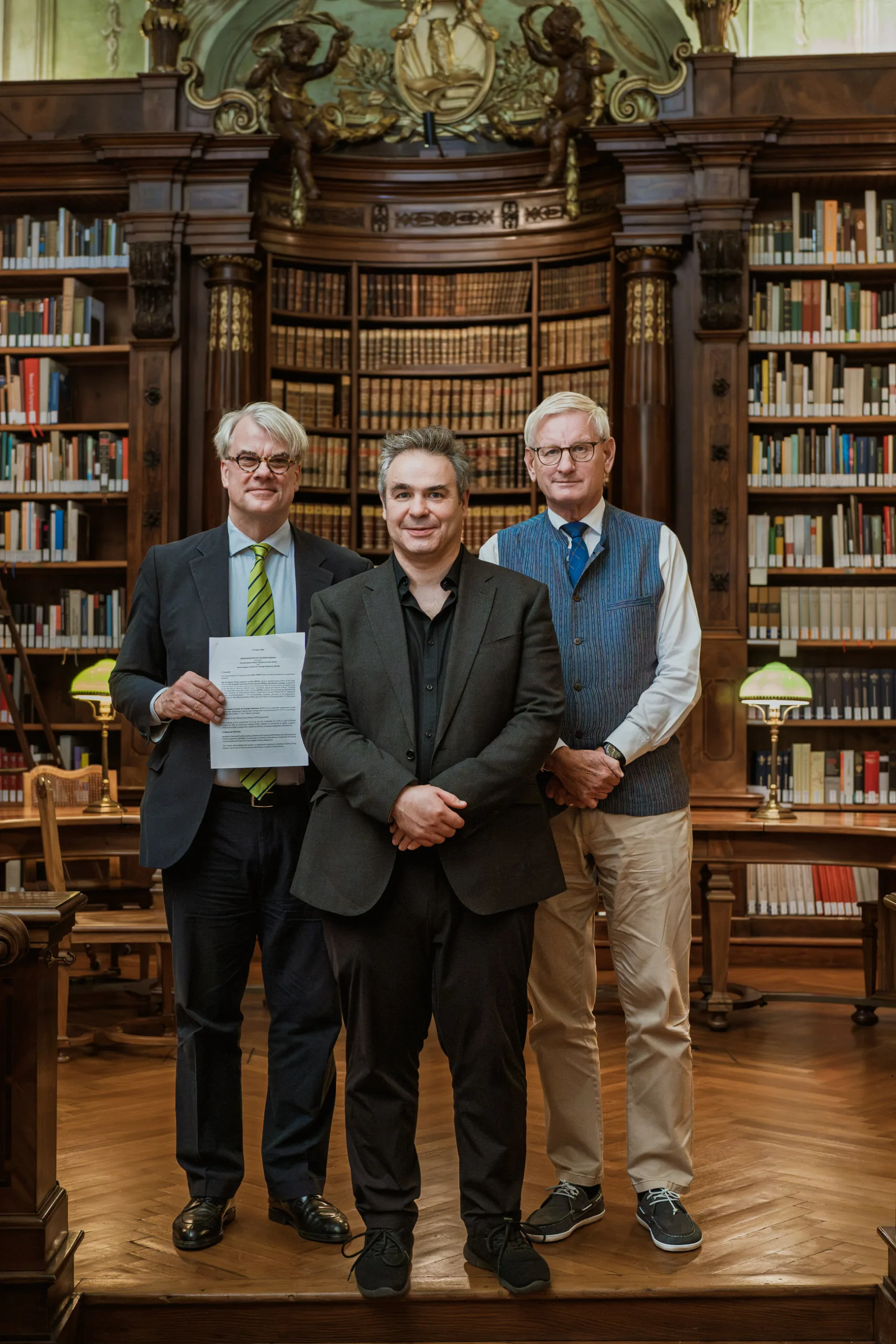 Portrait of three officials with a signed document in a beautiful library room in national austrian library by Berlin corporate photographer Fedor Vasilev