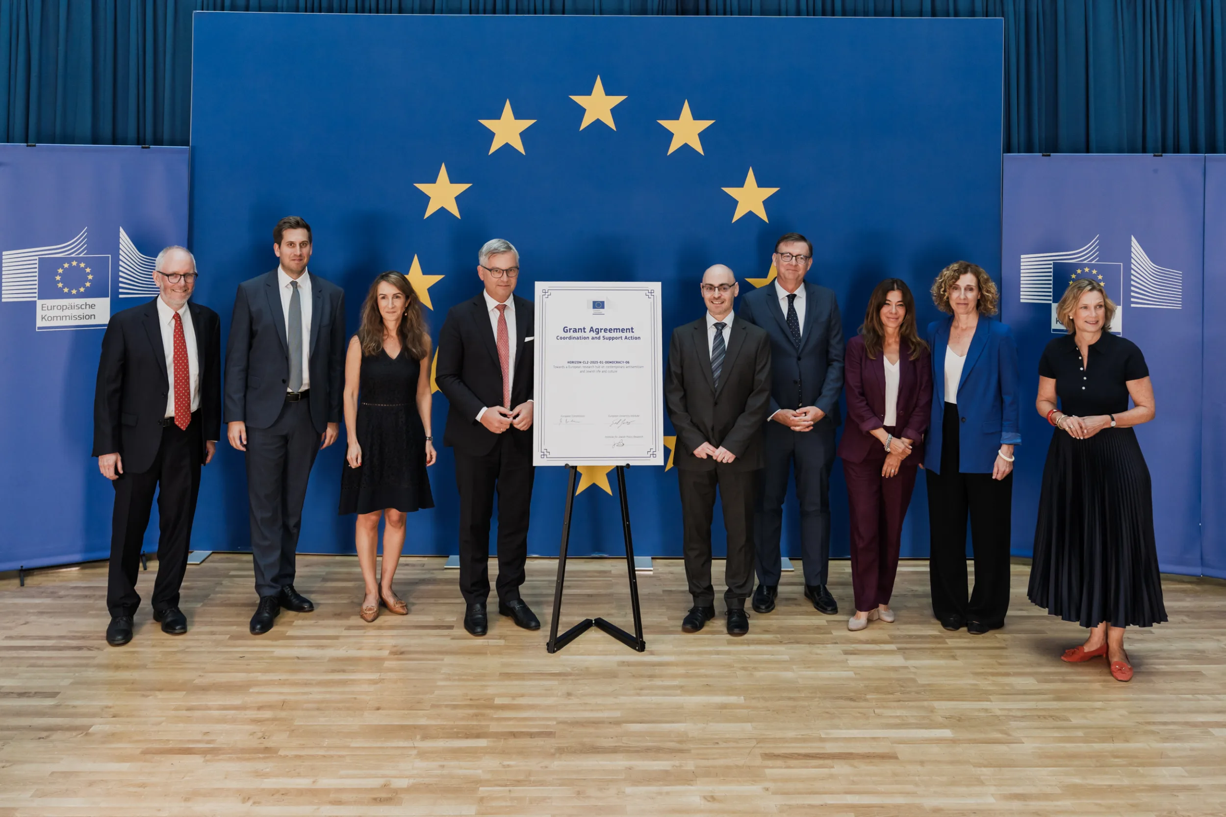 European Union Event Photographer | Grant Signing Ceremony in Vienna Fedor Vasilev Photographer In Berlin Nine professionals in formal attire stand in a line before a Grant Agreement document and the European Union flag.