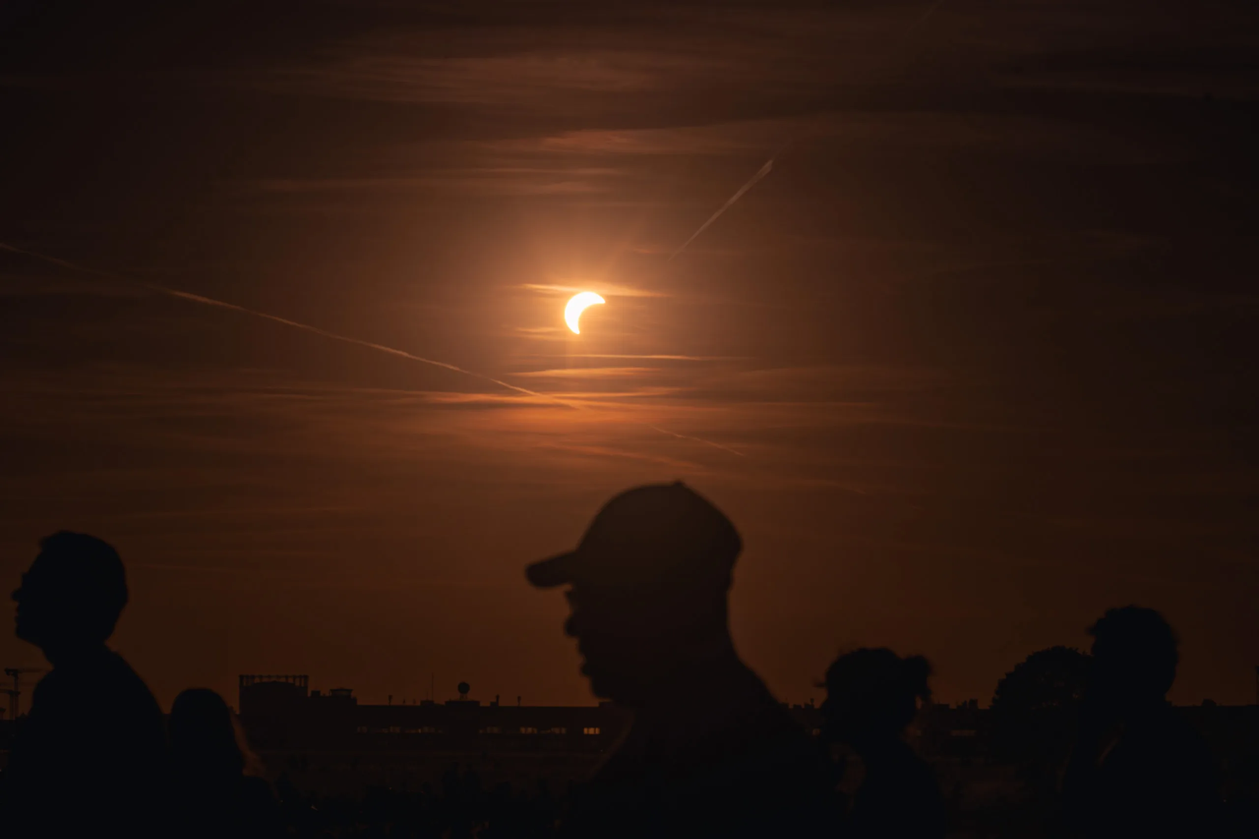 Photographing the Solar Eclipse in Berlin Fedor Vasilev Photographer In Berlin Silhouettes of people watching a partial solar eclipse in the orange evening sky, captured by Berlin-based photographer Fedor Vasilev.